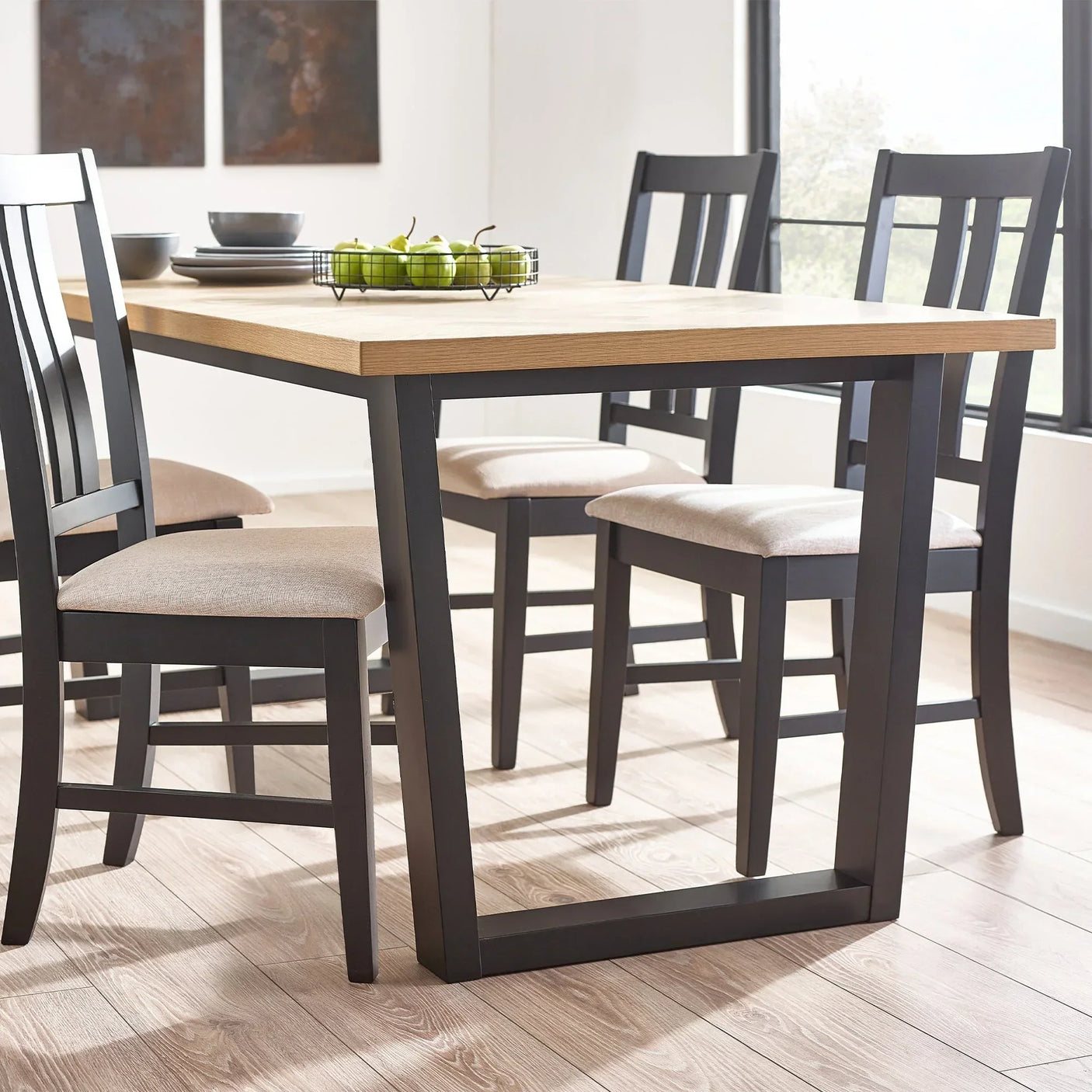 Wood dining table with black legs and four chairs in bright modern dining room