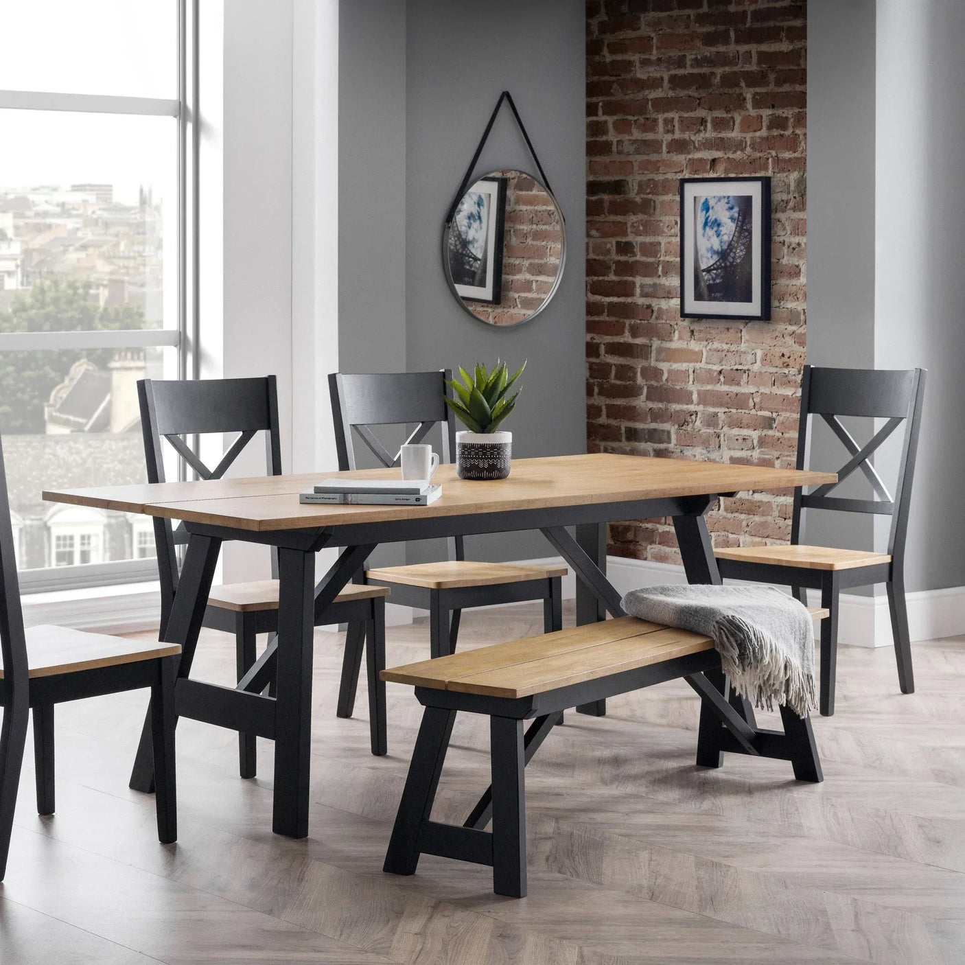 Wood dining table set with black chairs and bench, grey throw, in modern dining room