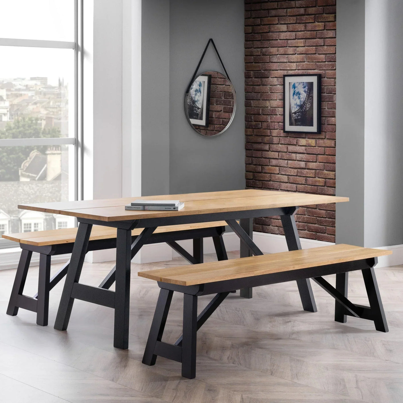 Oak dining table set with matching benches, black legs, in modern dining room with brick wall