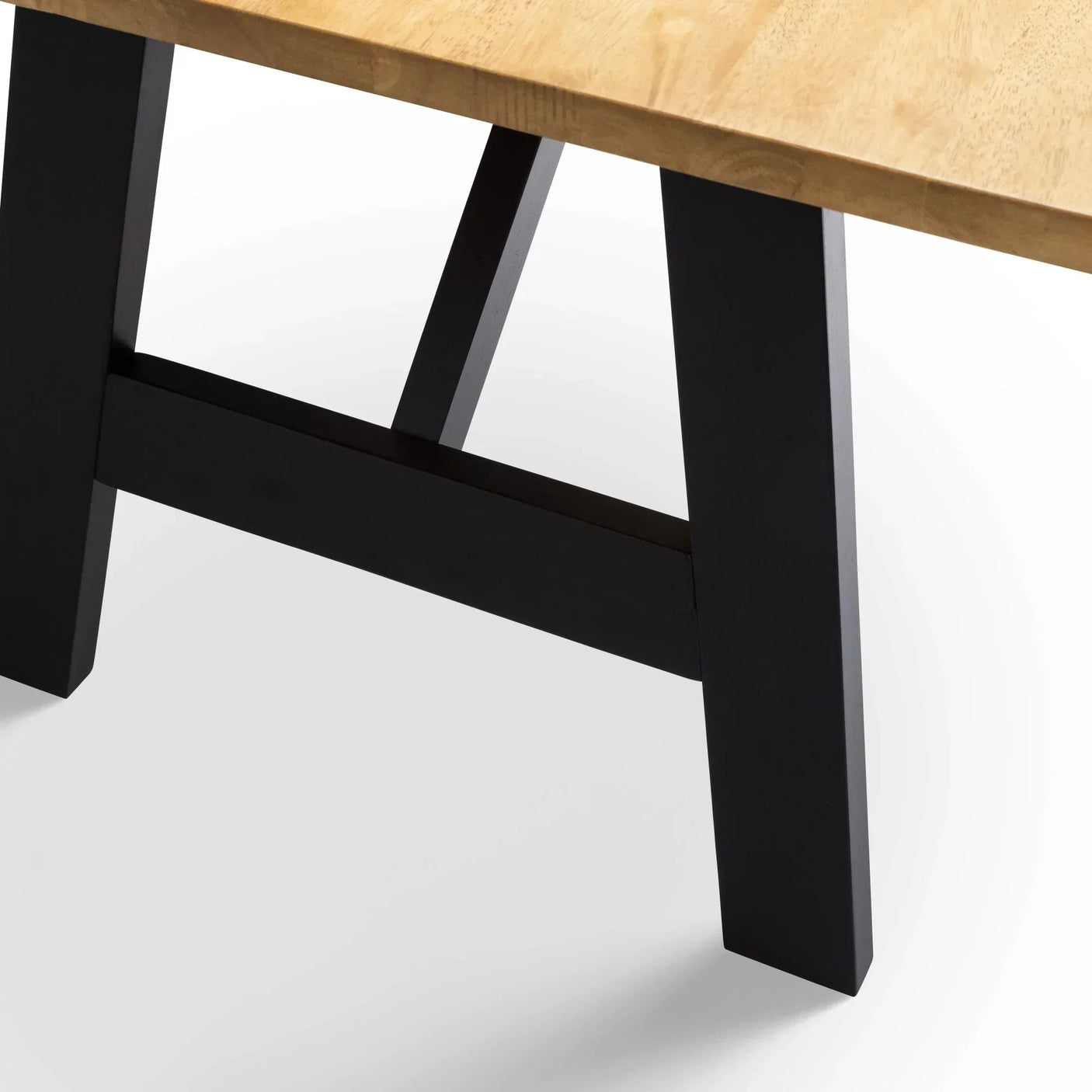 Wooden dining table corner with light wood top and black A-frame legs