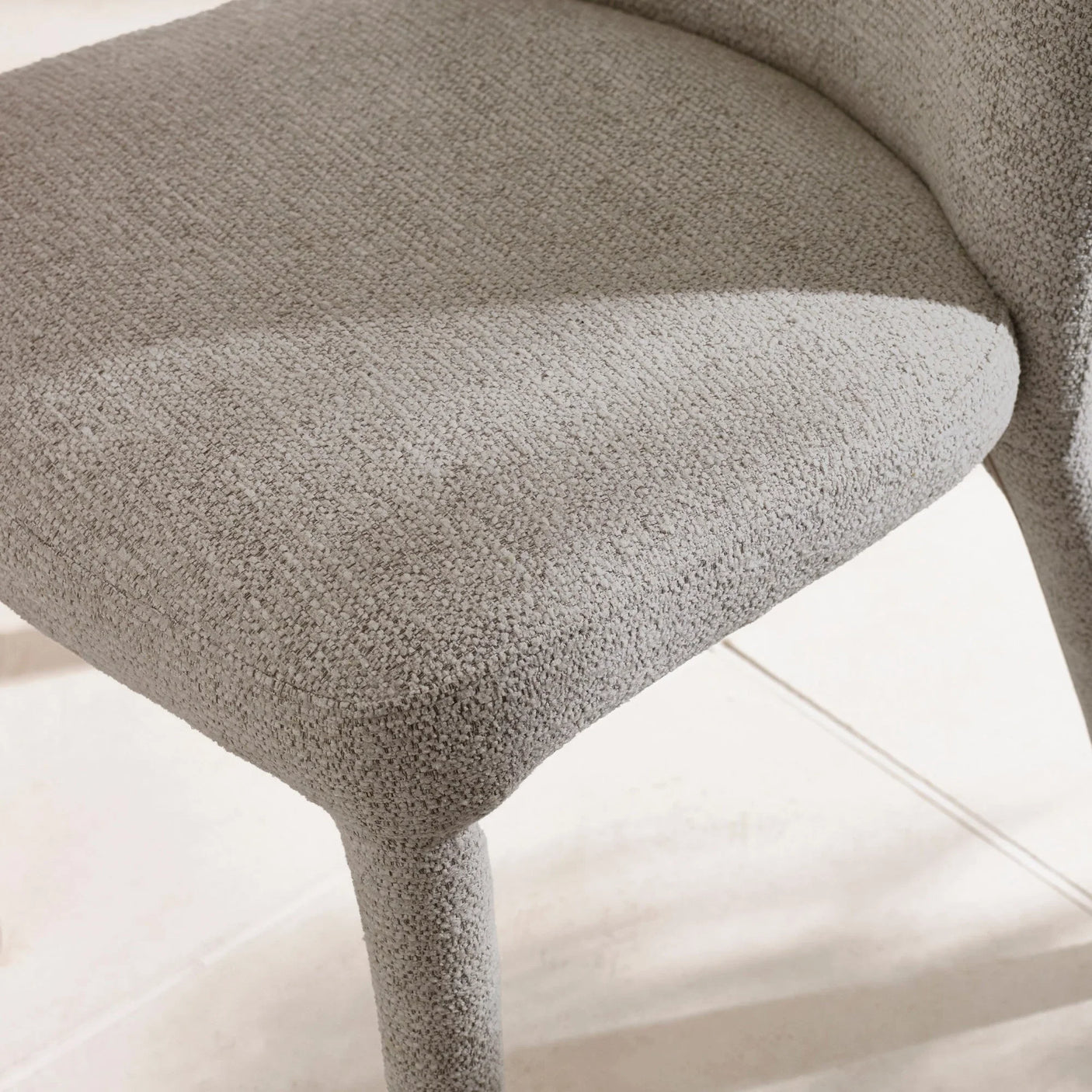 Light grey fabric dining chair seat and legs close-up on tiled floor