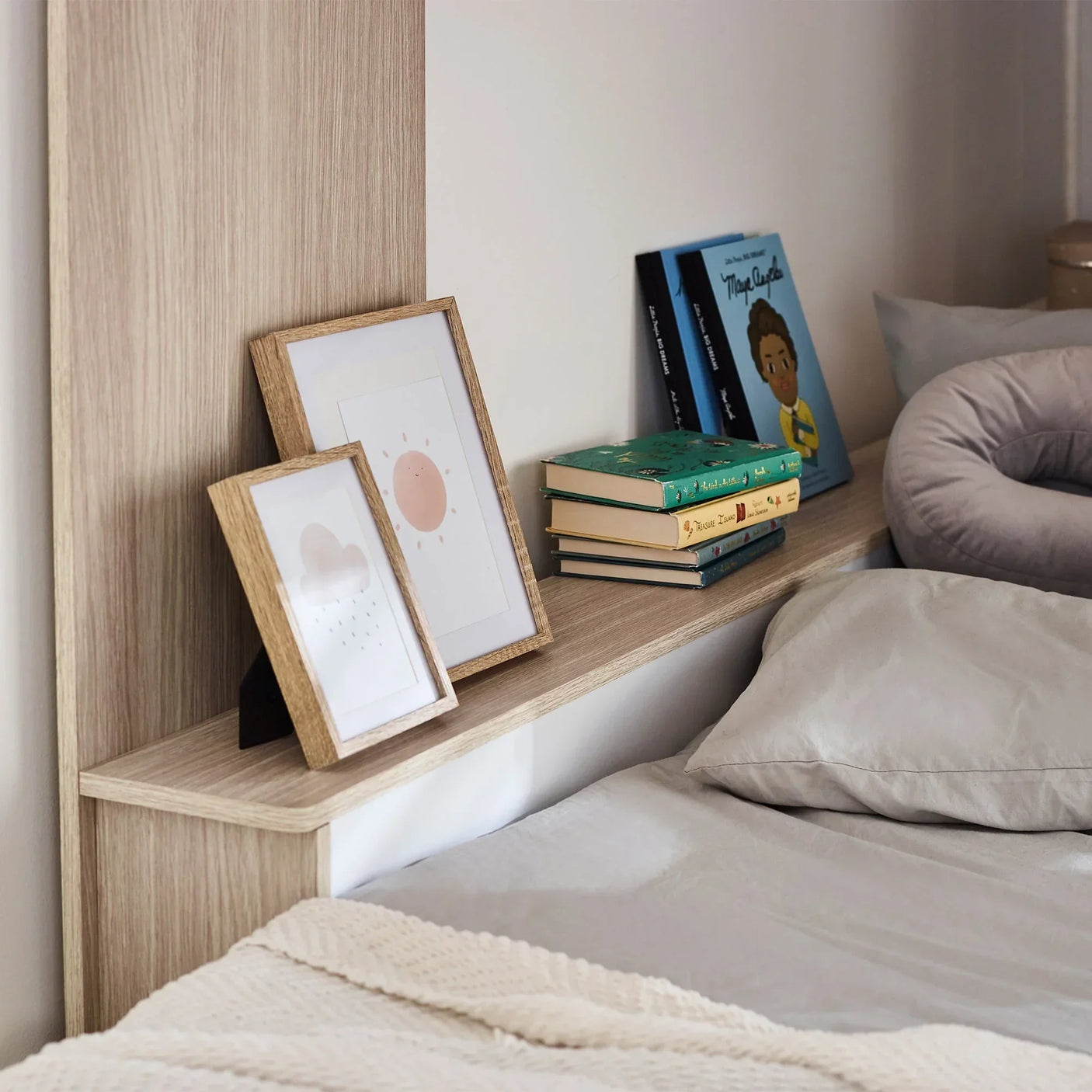 Horizon bunk bed pale wood shelf with books, framed prints, and grey bedding detail
