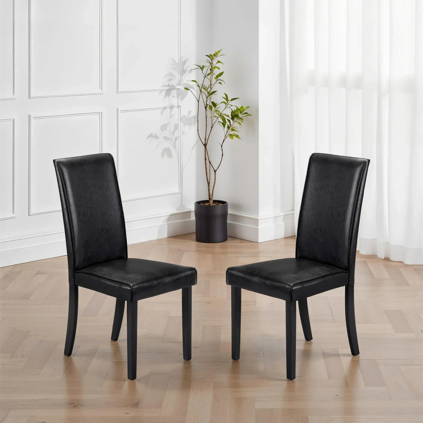 Black faux leather dining chairs with padded seats in modern living room setting