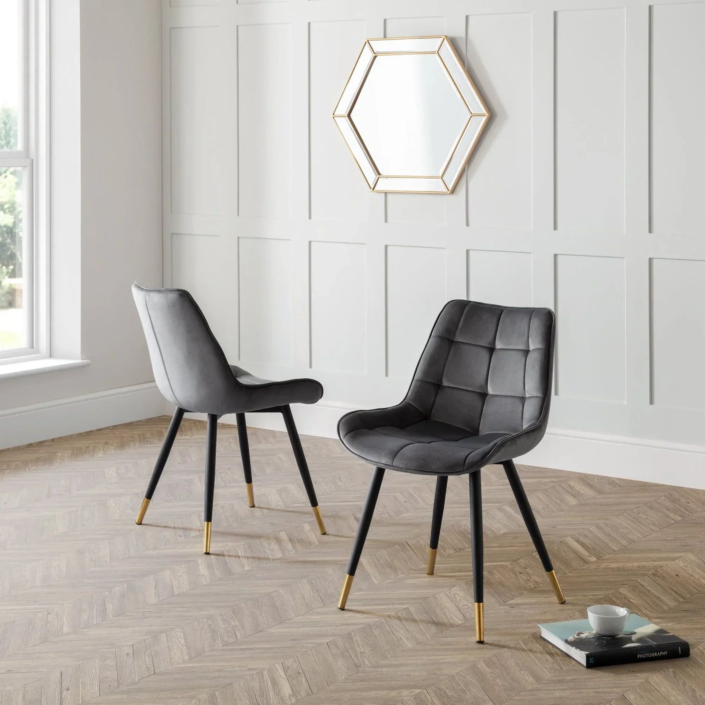 Grey dining chairs with gold-tipped legs on herringbone floor in modern living room