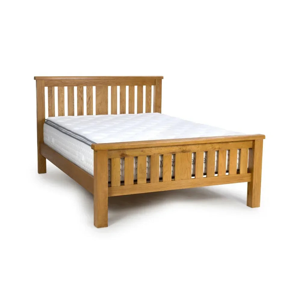 Oak wooden bed frame with slatted headboard and footboard, shown with white mattress