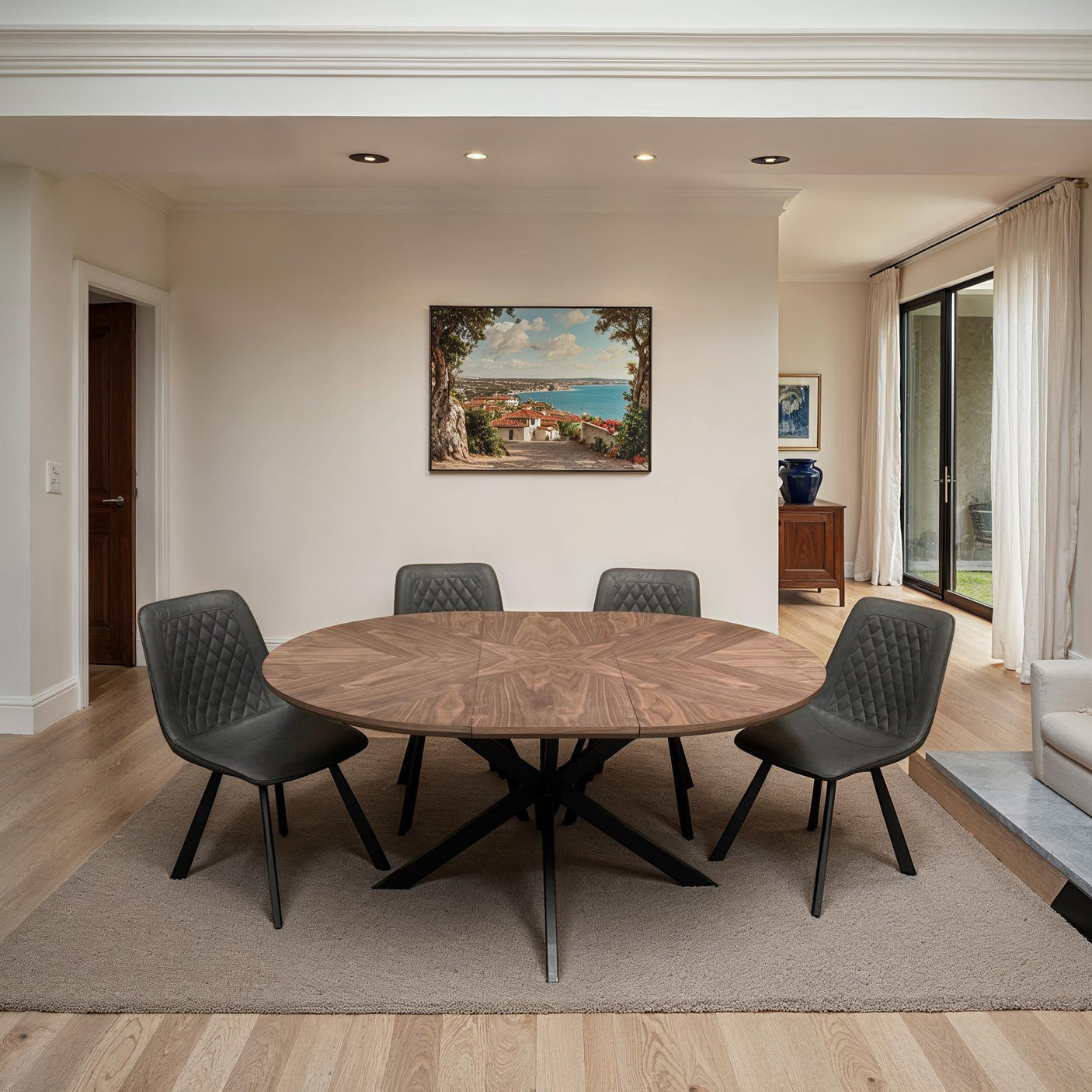 Round wooden dining table with black metal legs and four retro grey chairs in modern room