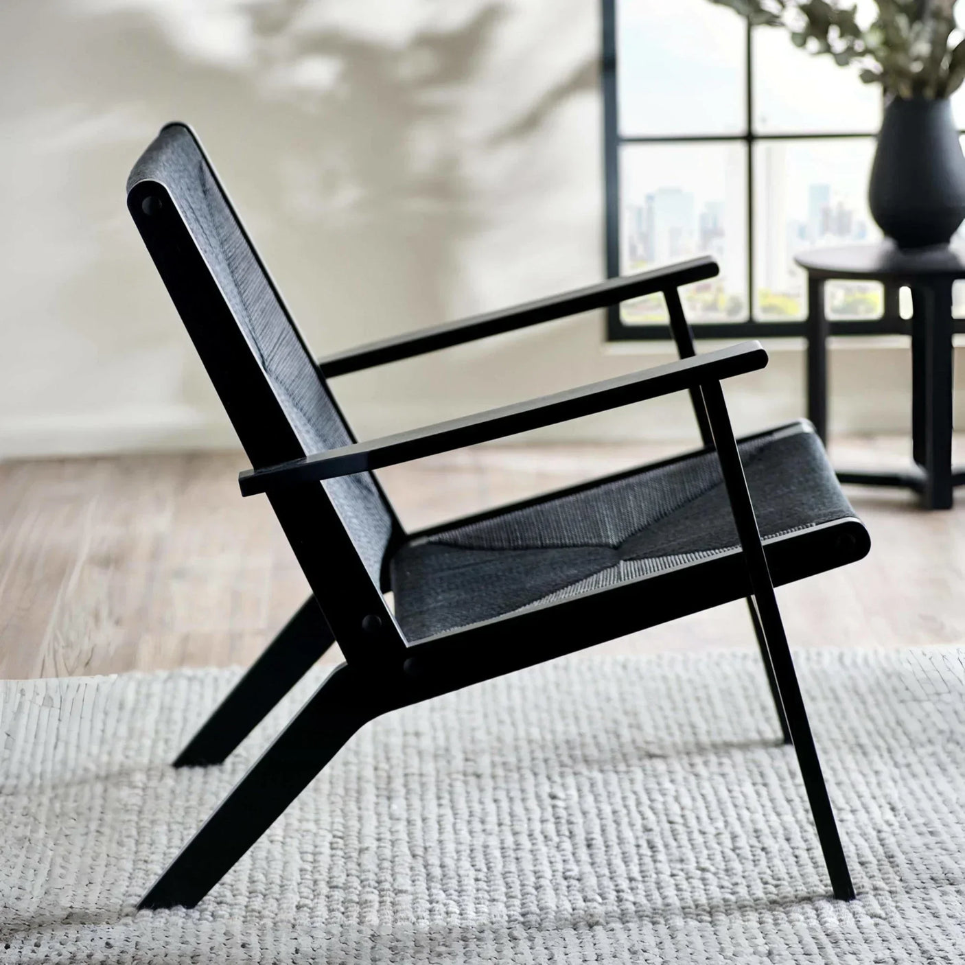 Black lounge chair with mesh seat on light rug in modern living room