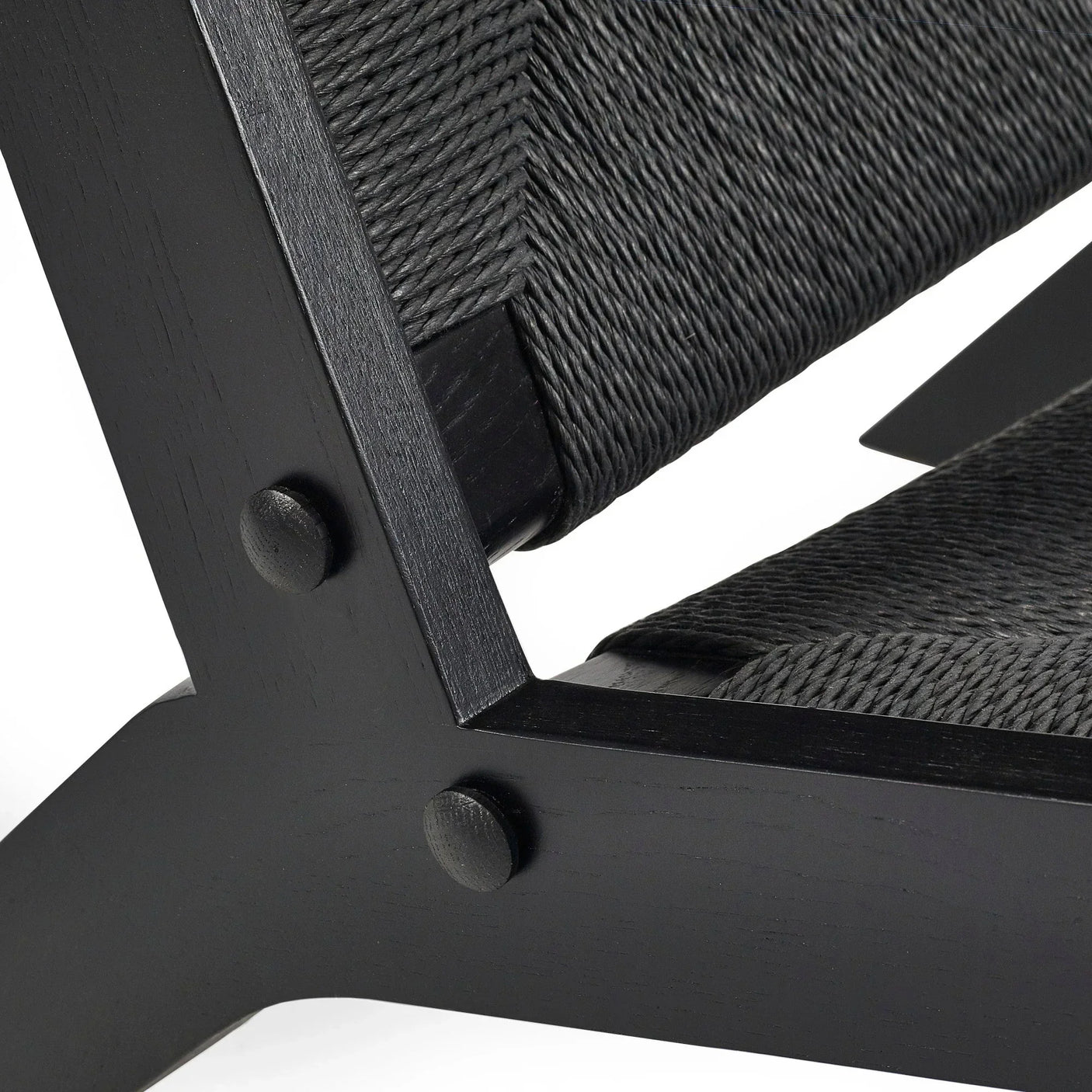 Closeup of black woven chair seat with textured wooden frame and angled join detail
