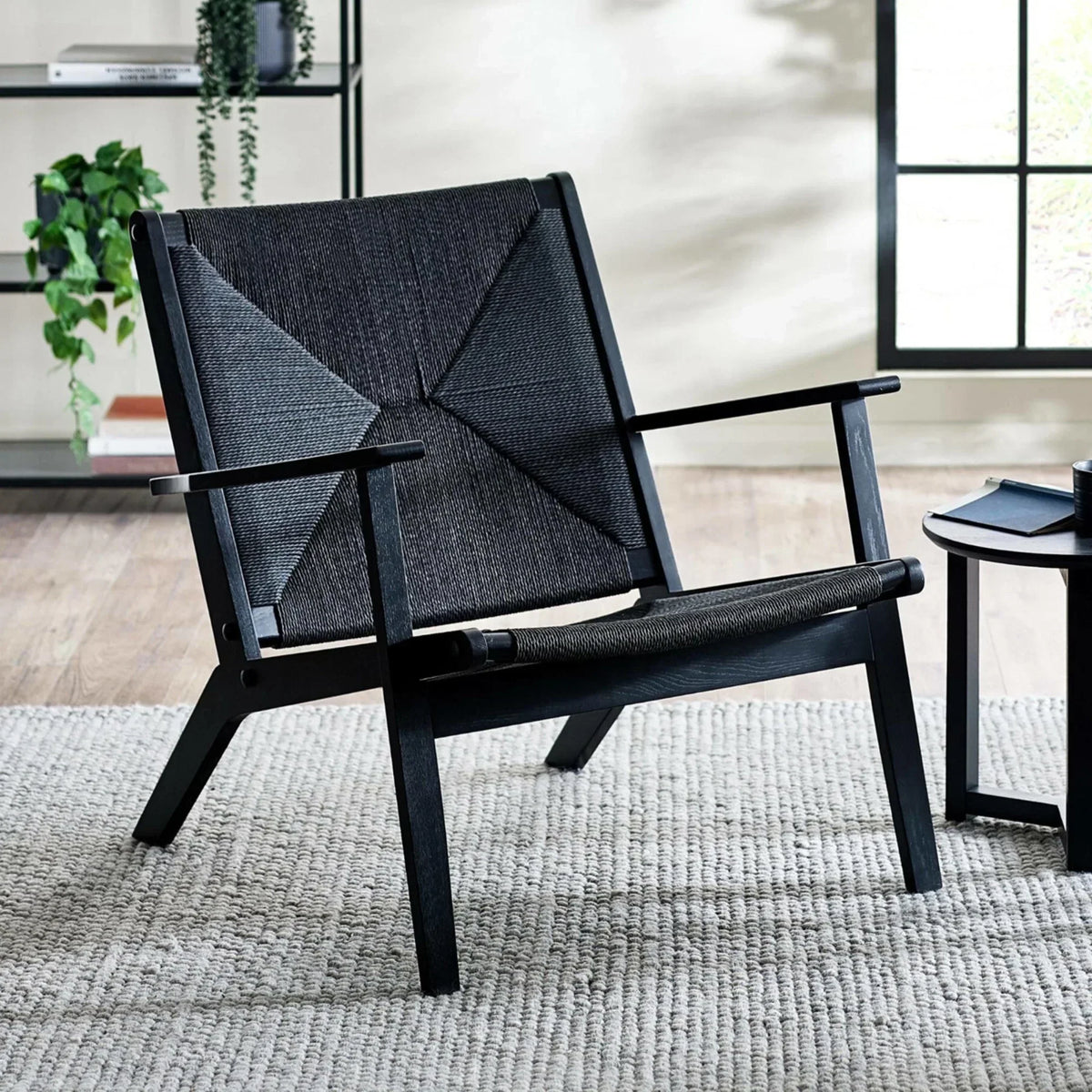 Black lounge chair with geometric woven seat and back in modern living room