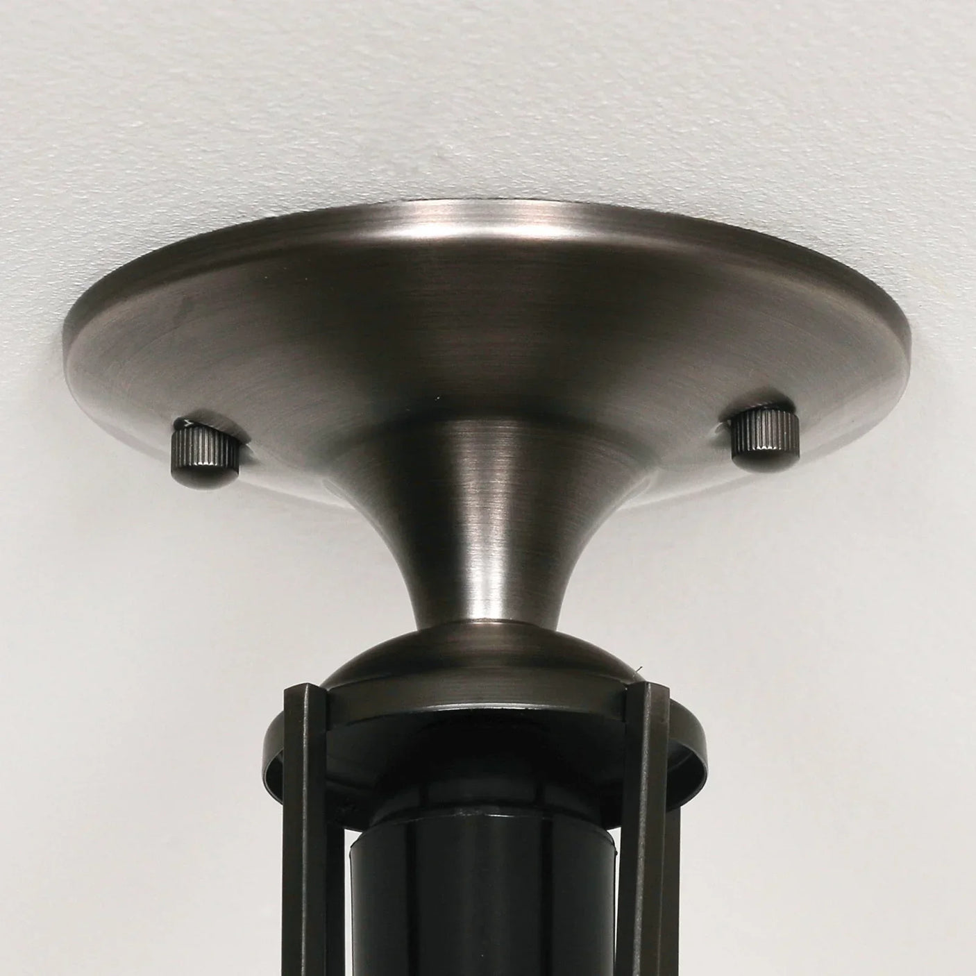 Brushed metal ceiling light fixture mount with dark cylindrical stem, close-up view