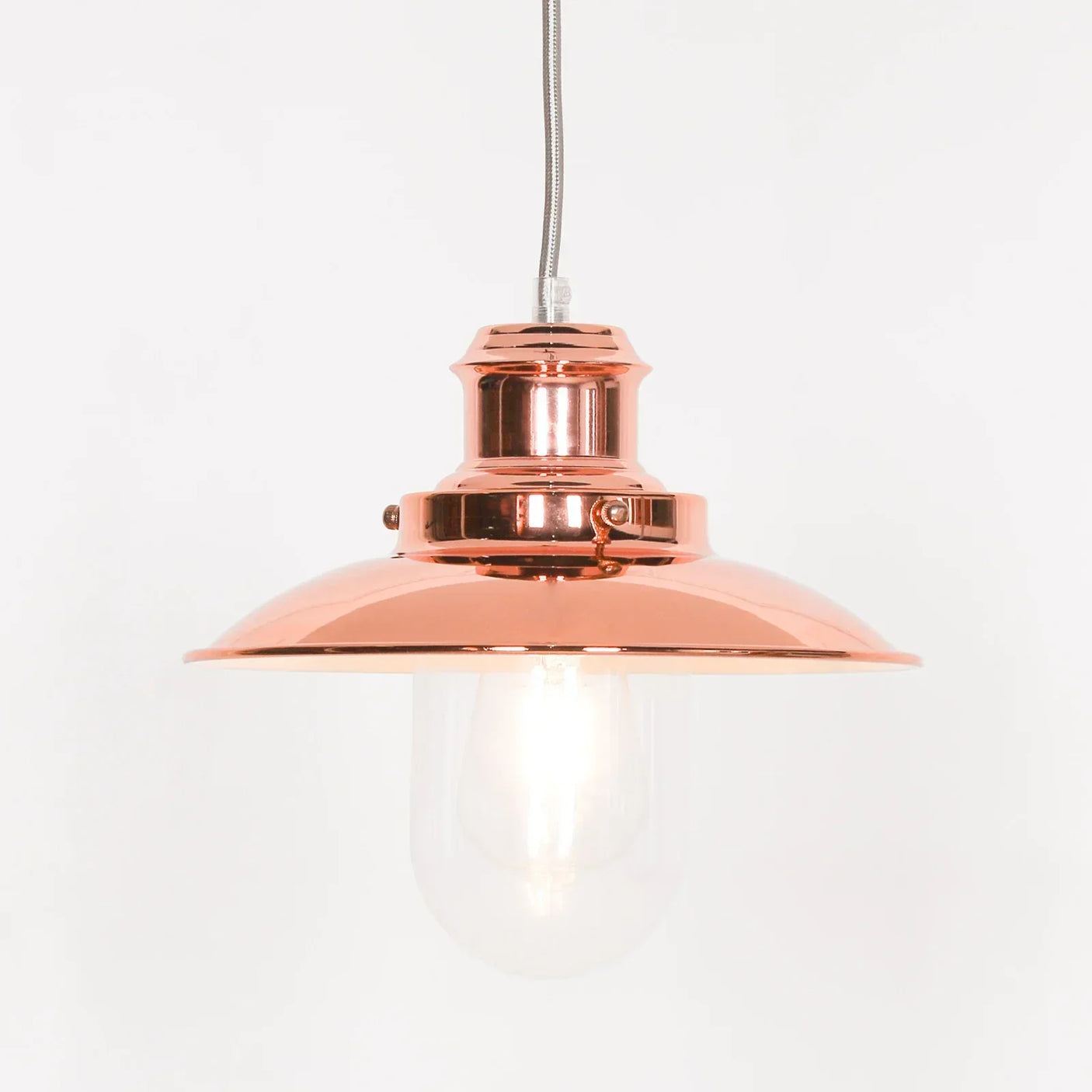 Copper pendant ceiling light with glass shade and exposed bulb on white background