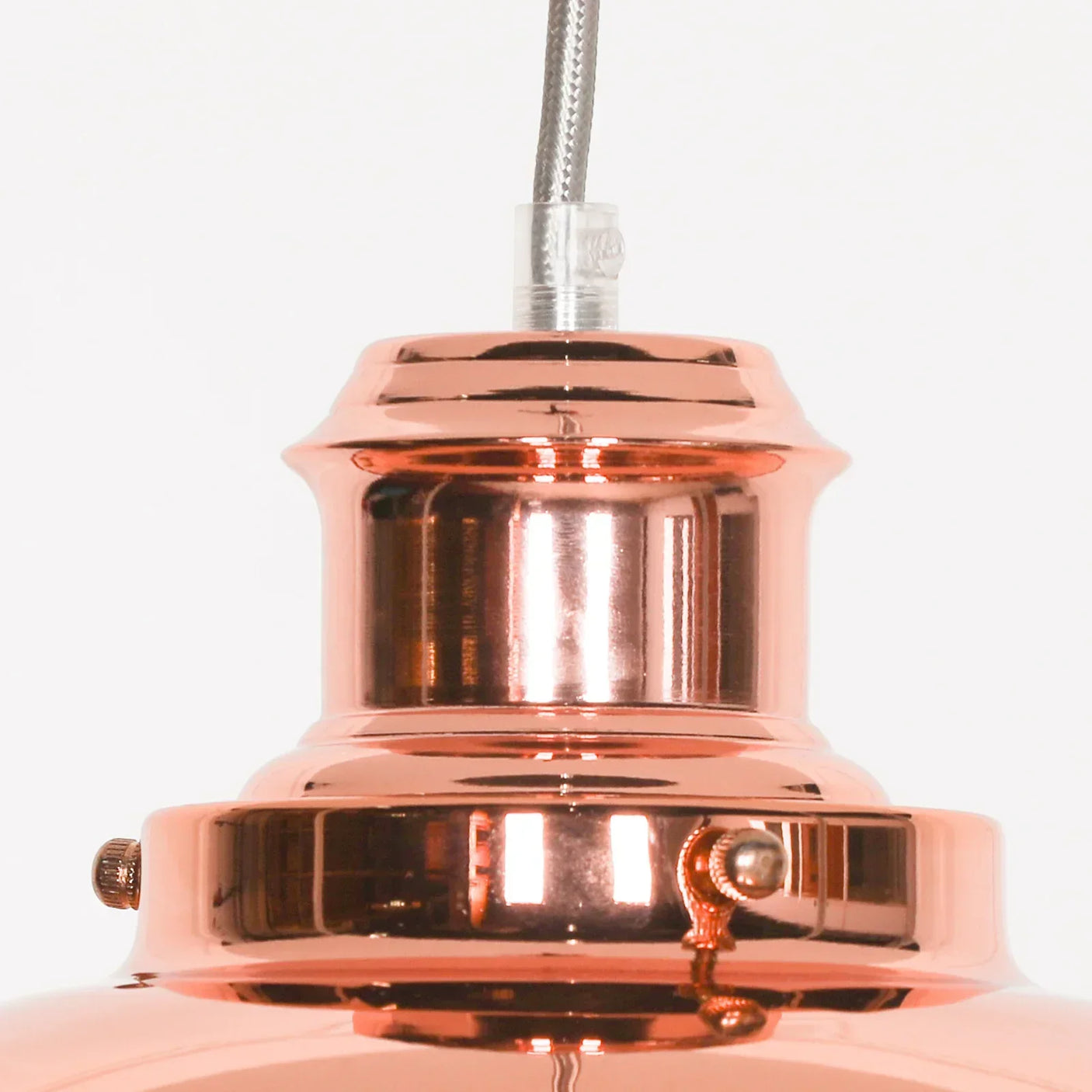 Close-up of copper pendant light fixture with polished metal finish and hanging cable
