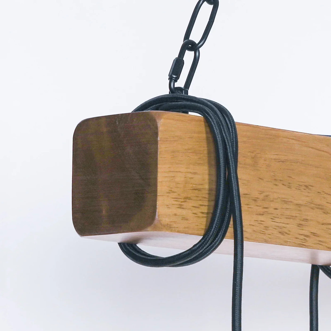 Close-up of wooden pendant light with black hanging chain and cord detail