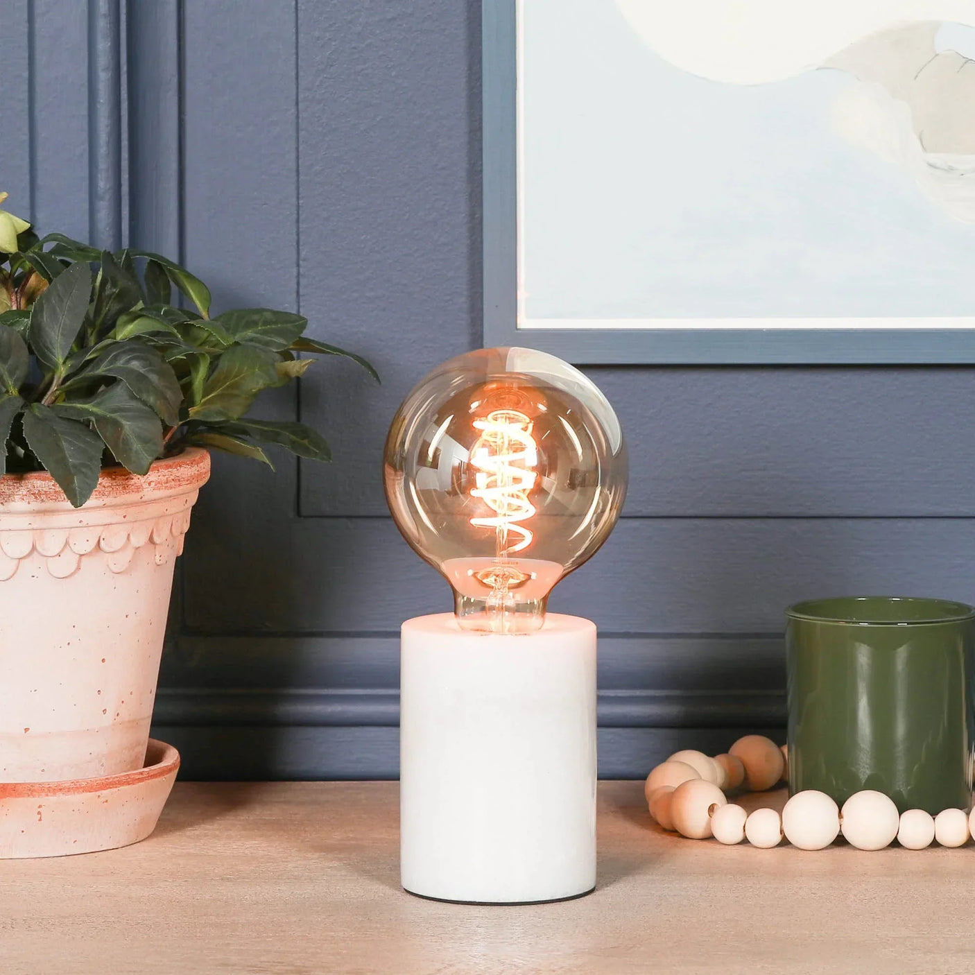 Modern table lamp with round bulb and white marble base on wooden surface