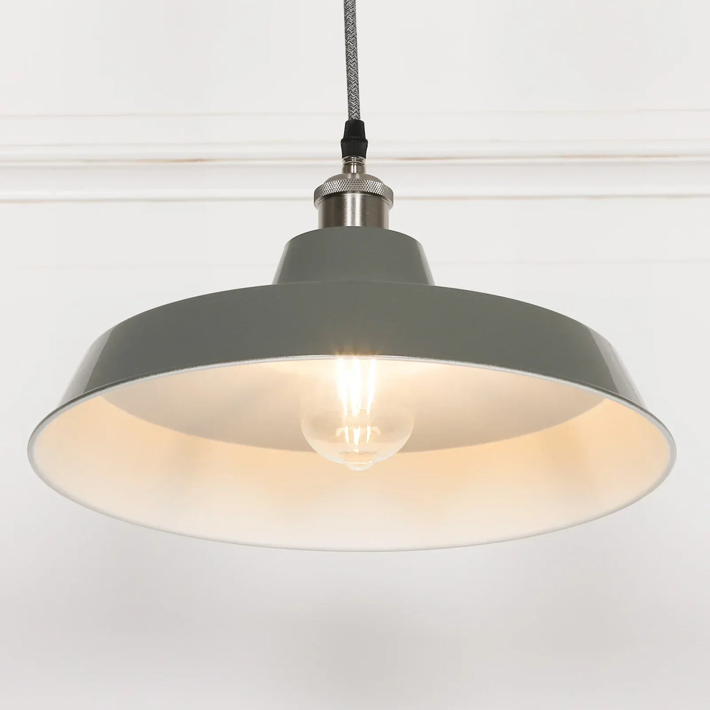 Grey metal pendant light with exposed bulb hanging from ceiling