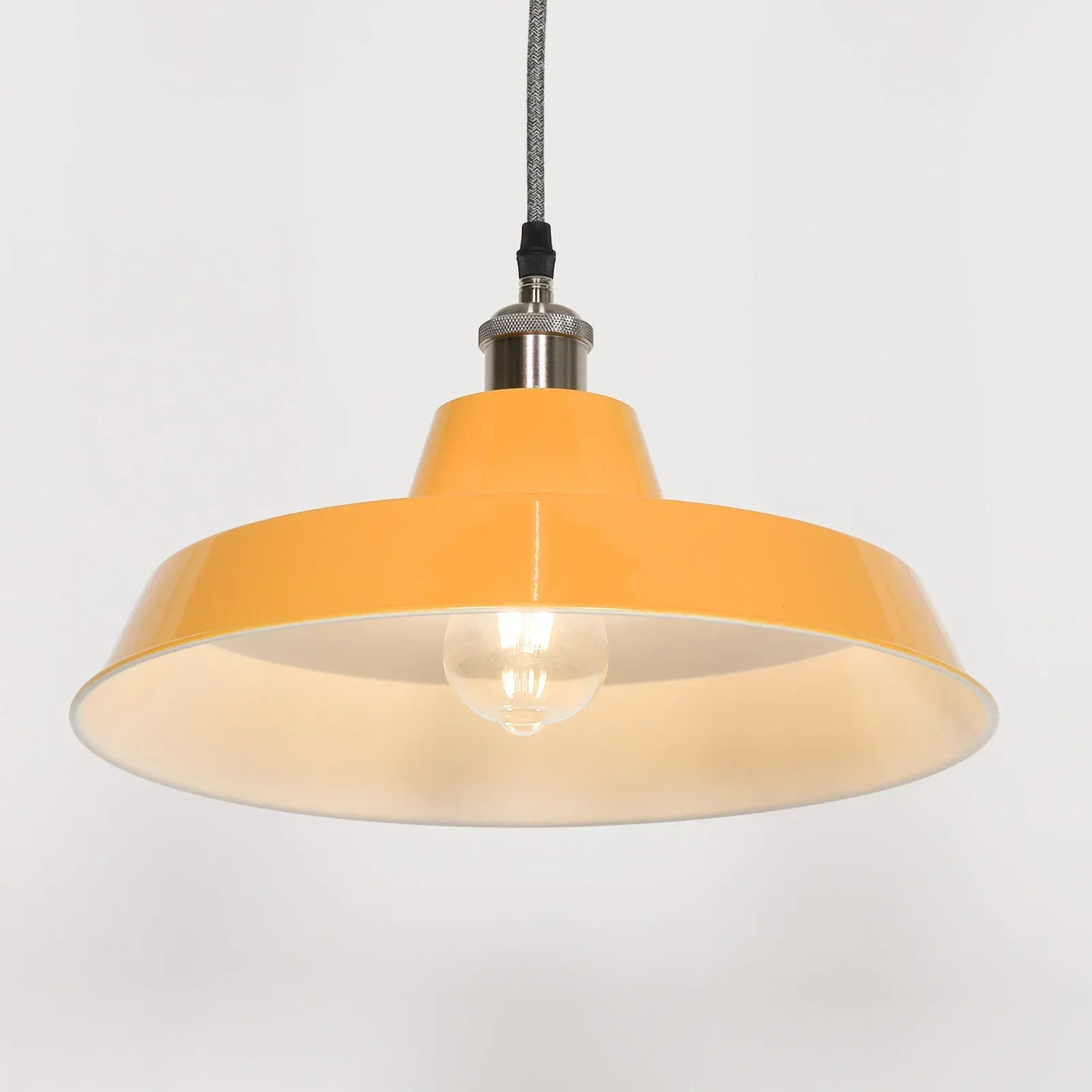 Yellow metal pendant light with exposed bulb and fabric cord, viewed from below