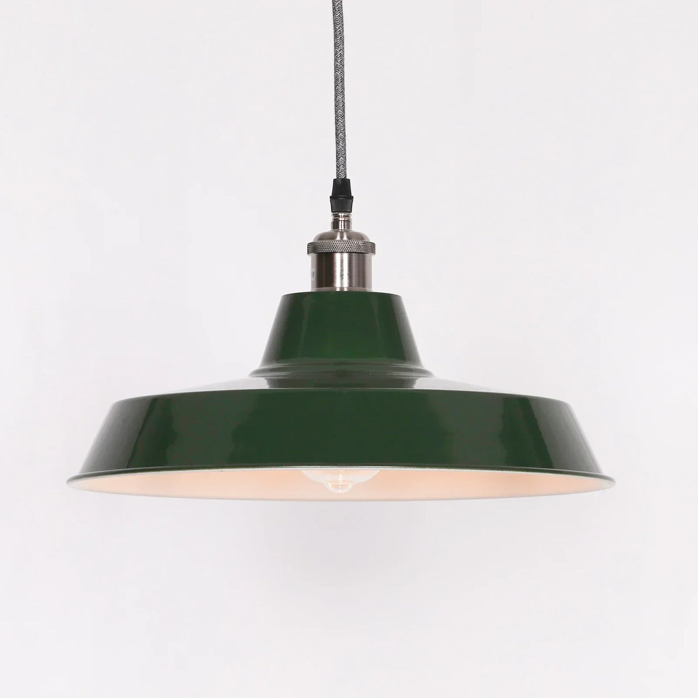 Green metal pendant light with wide shade and exposed bulb hanging from cord