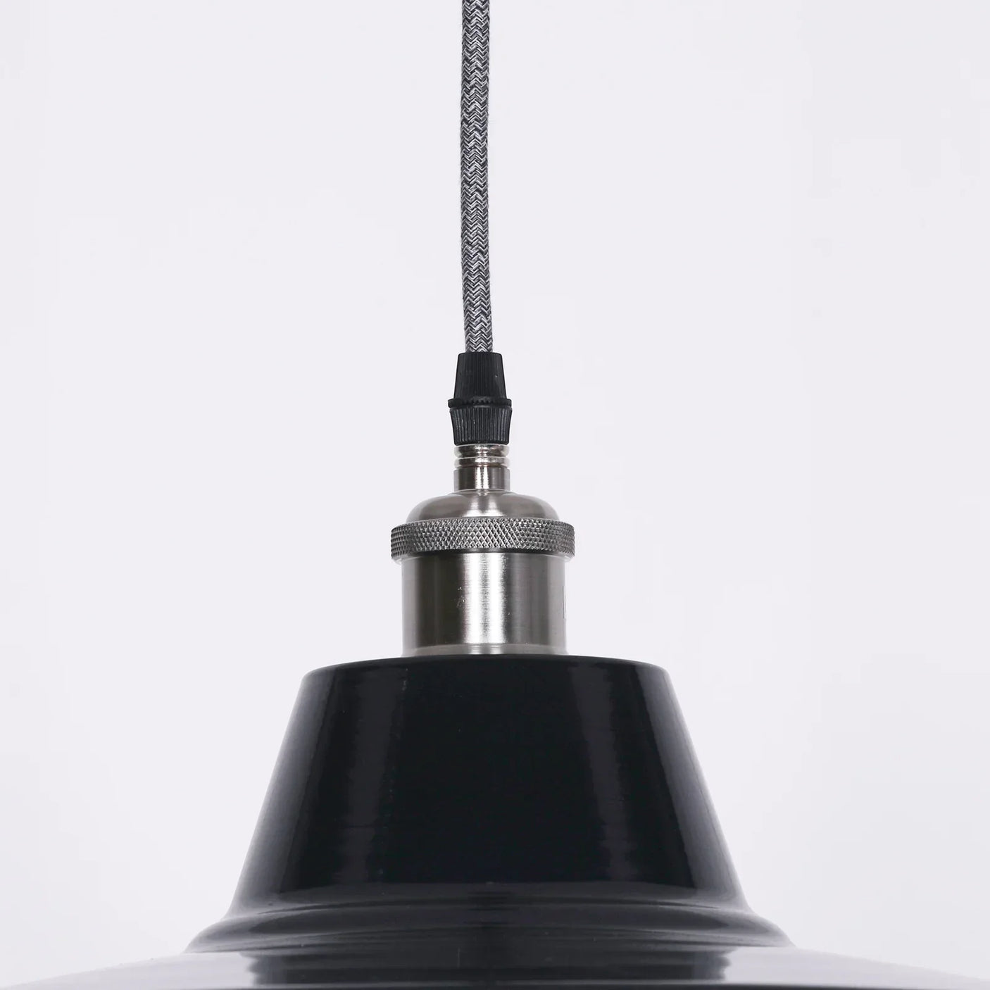 Close-up of black metal pendant light with chrome fixture and braided cable