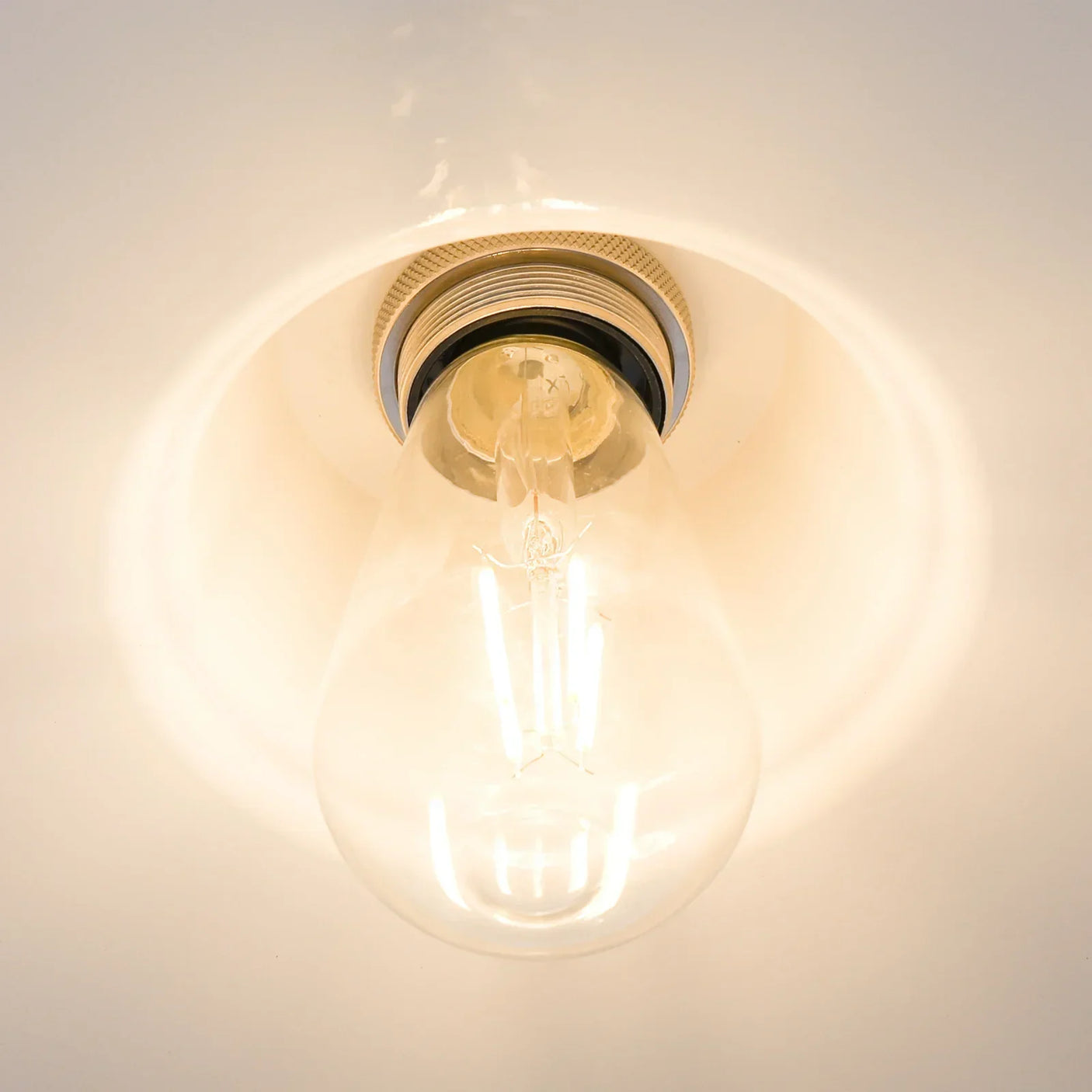 Close-up view of LED ceiling light fixture with exposed bulb and warm white glow