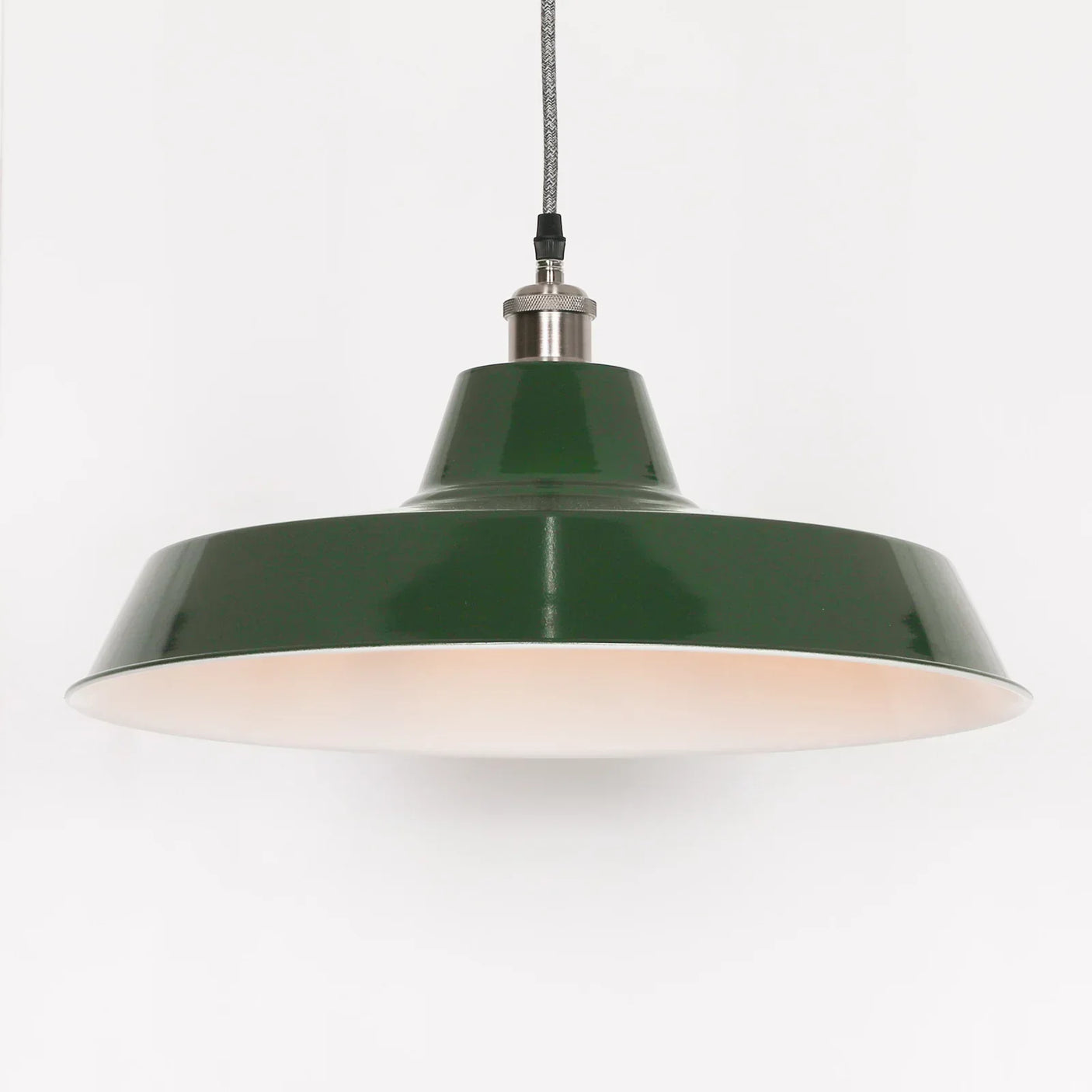 Green metal pendant light with wide shade and fabric cord against white background