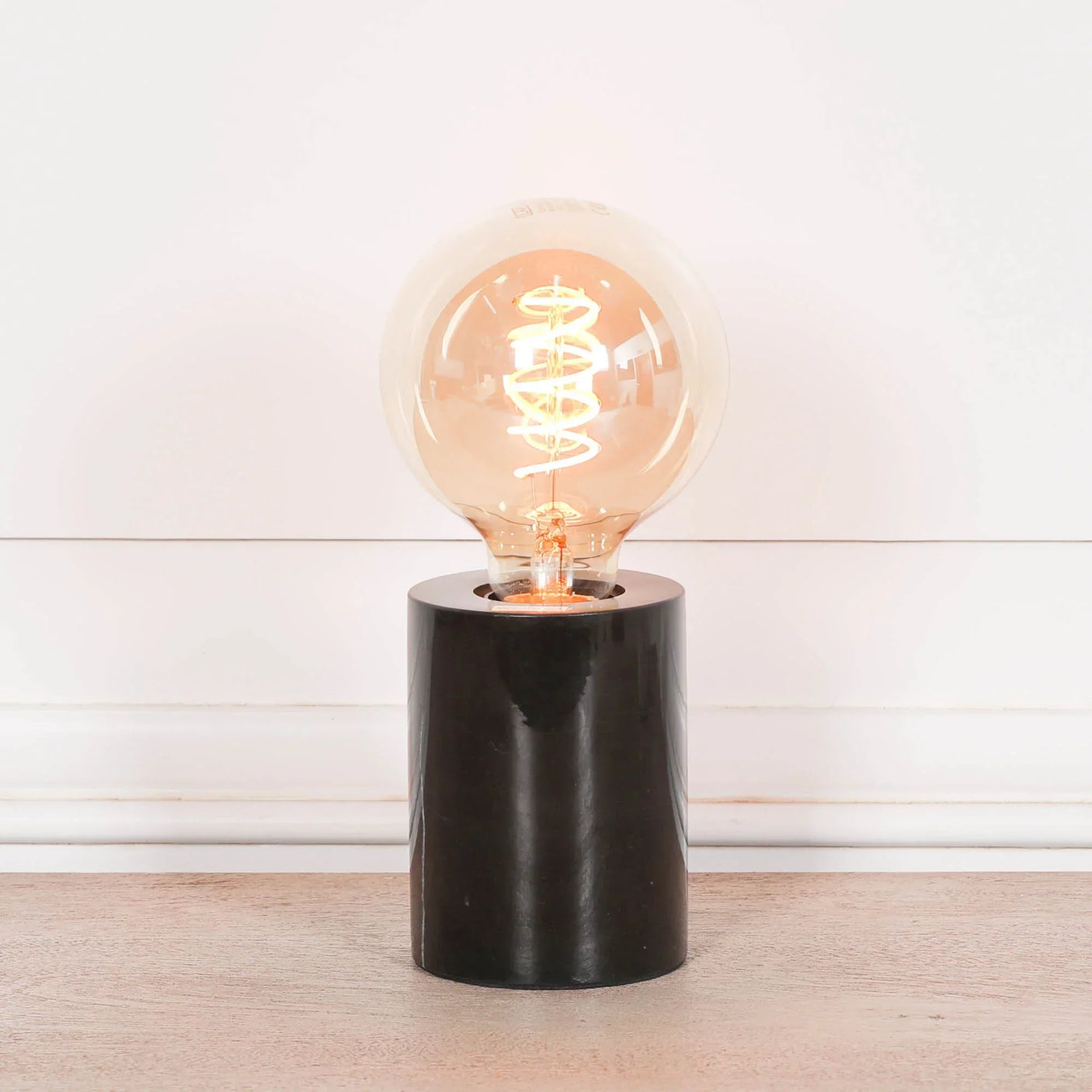 table lamp with exposed filament bulb on black cylindrical base