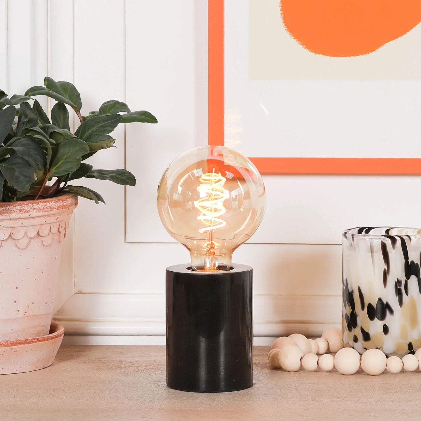 modern table lamp with black cylindrical base and round bulb on wooden surface