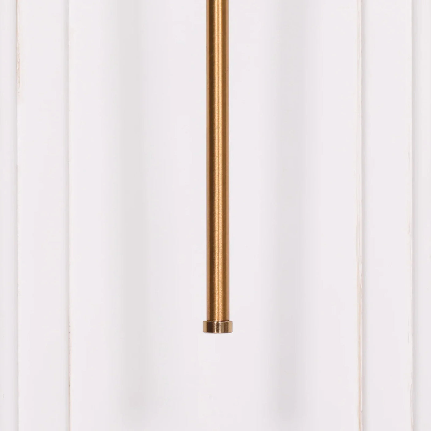 Closeup of gold metal pendant light rod against white wall panel