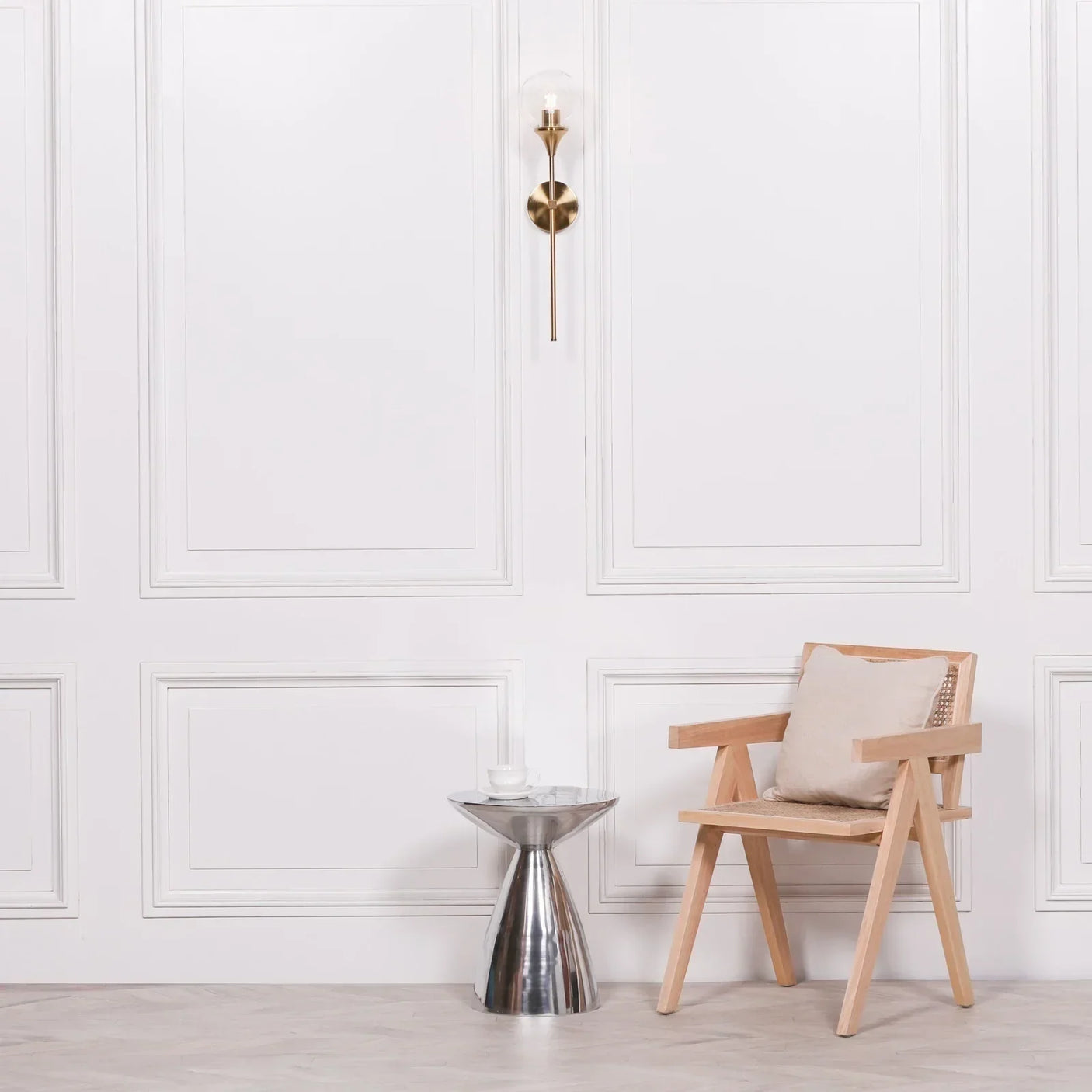 Wooden accent chair with neutral cushion beside metallic side table and white panel wall