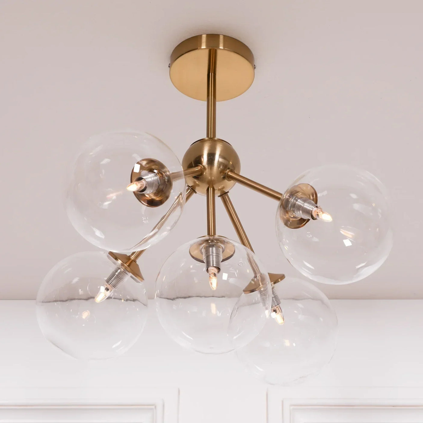 Modern brass ceiling light with six clear glass globe shades and exposed bulbs
