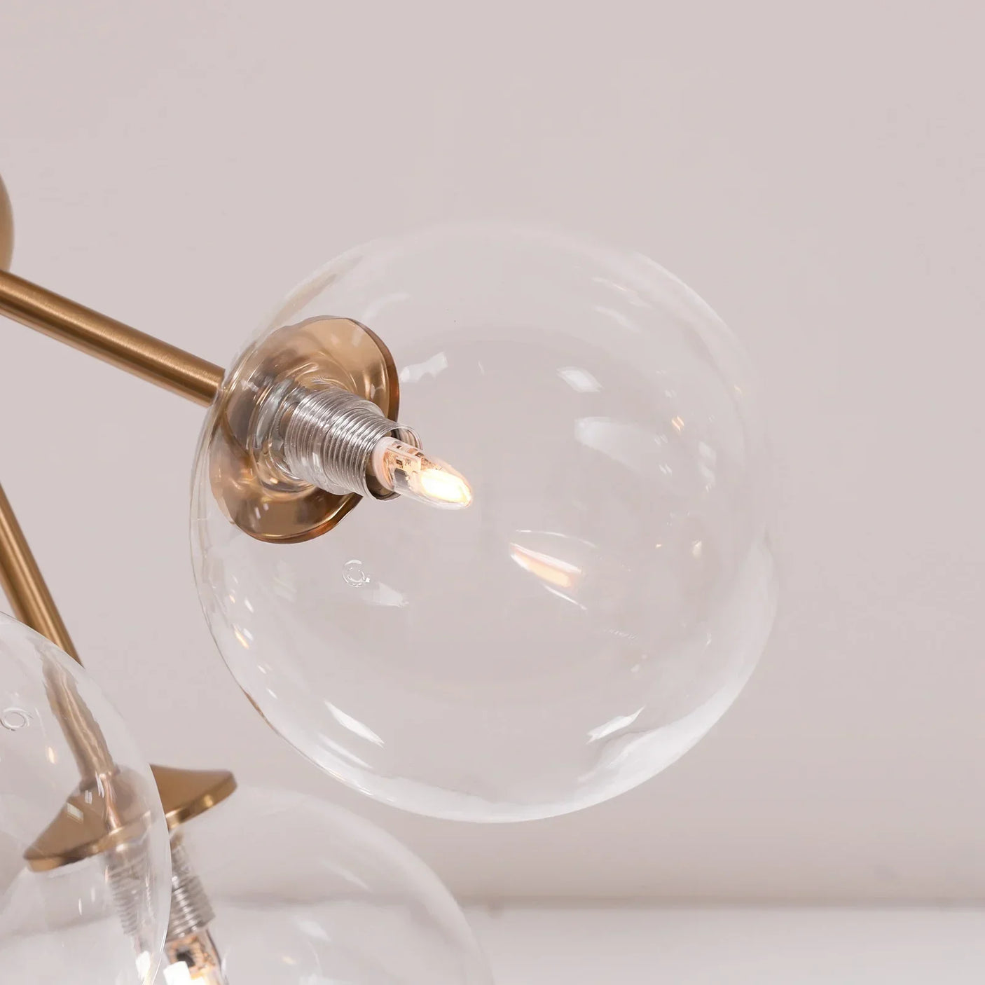 Close up of modern glass globe ceiling light with gold fixture and exposed bulb