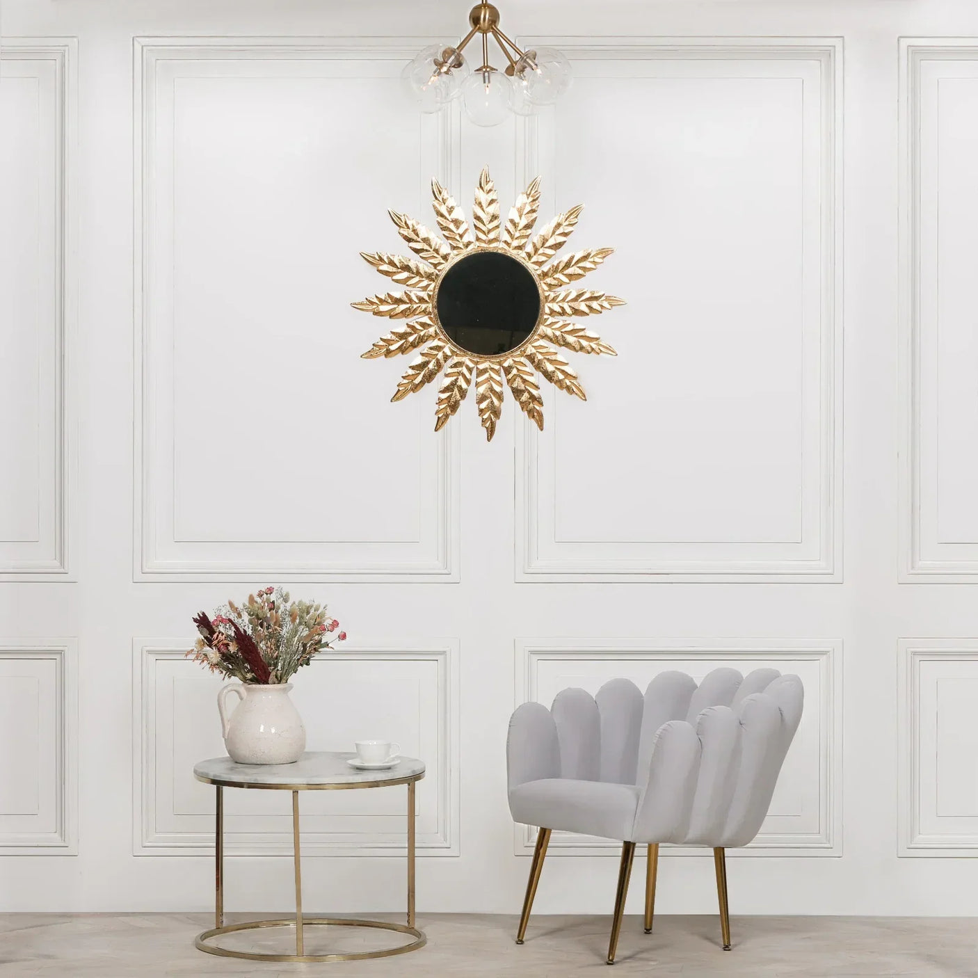 Grey scallop accent chair with gold legs beside marble side table and floral decor