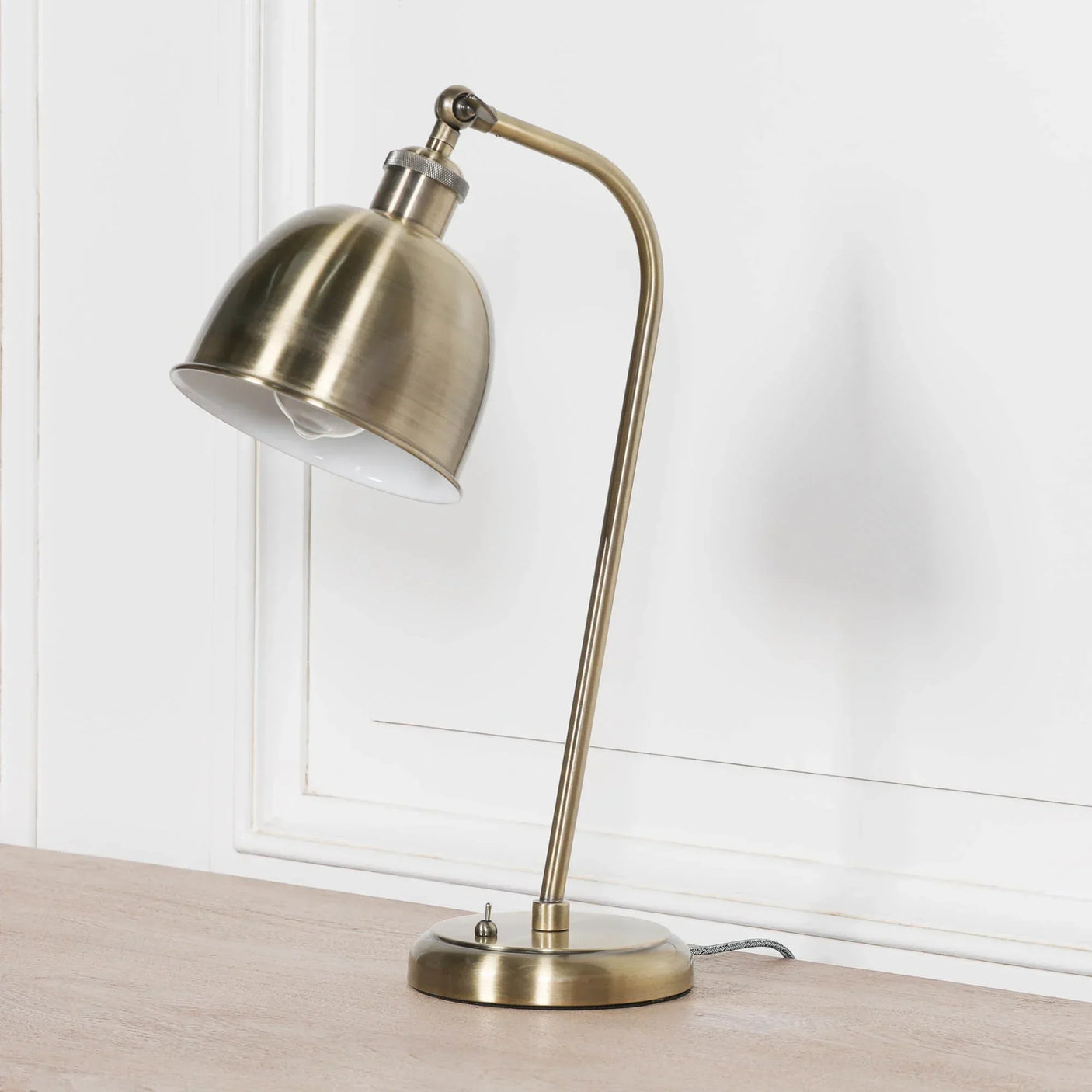 Brushed brass desk lamp with dome shade on wooden surface