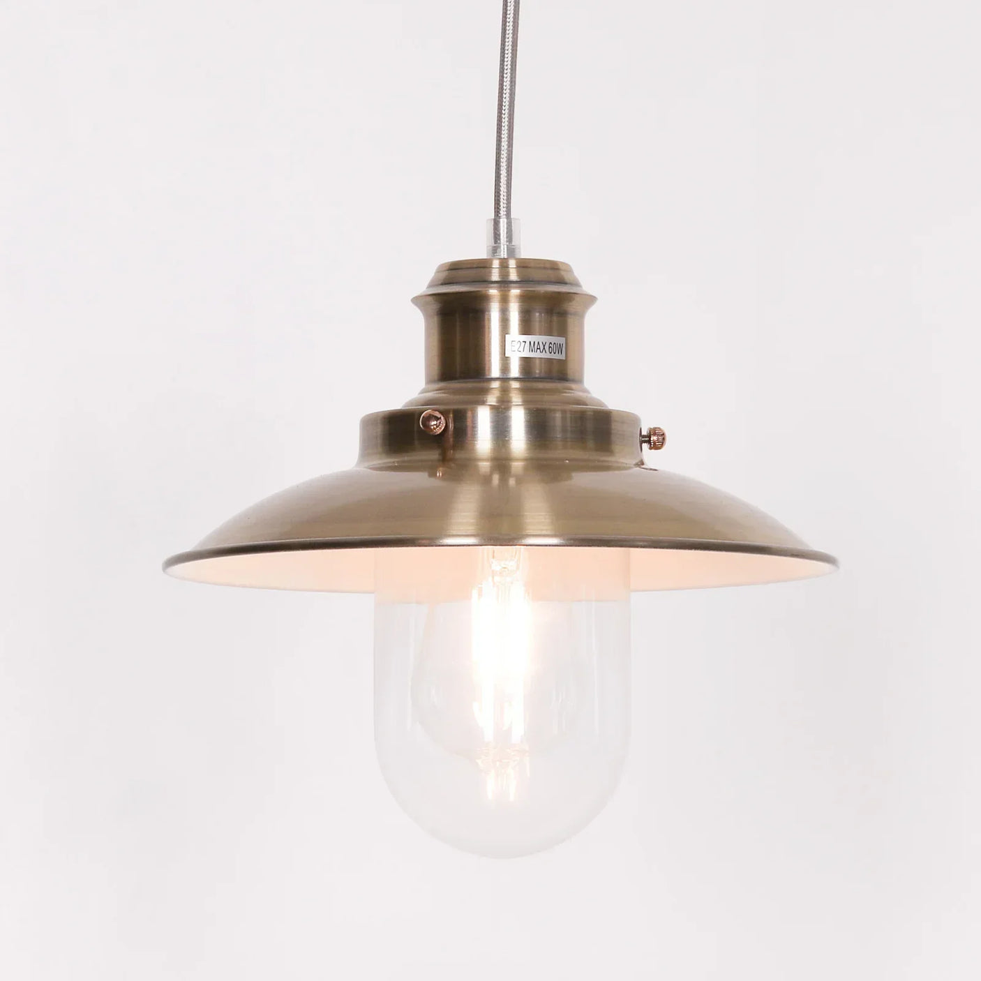 Brass pendant light with clear glass shade and exposed bulb against white background