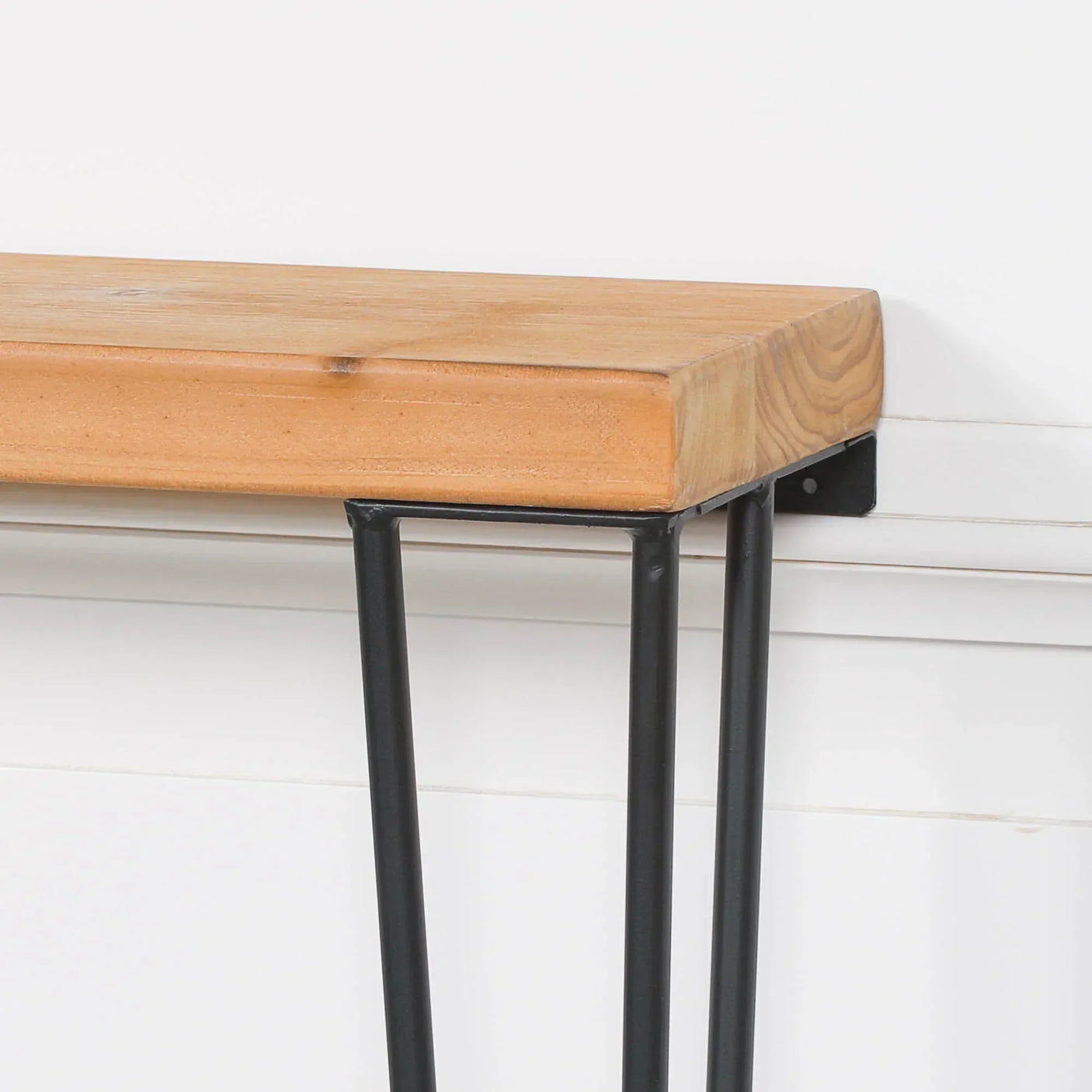 Closeup of wooden console table with black metal legs against white wall