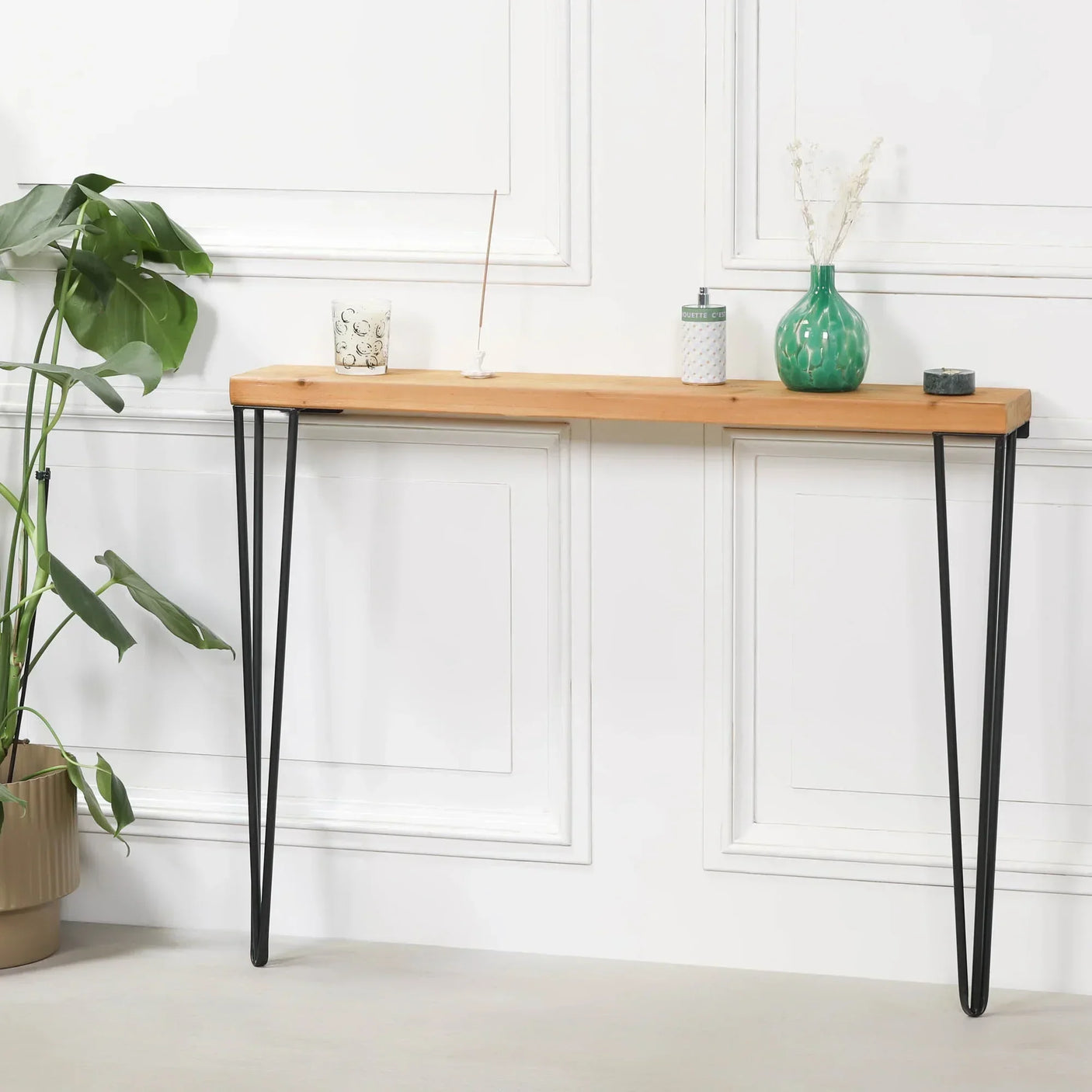 Narrow console table with wooden top and black metal hairpin legs against white wall
