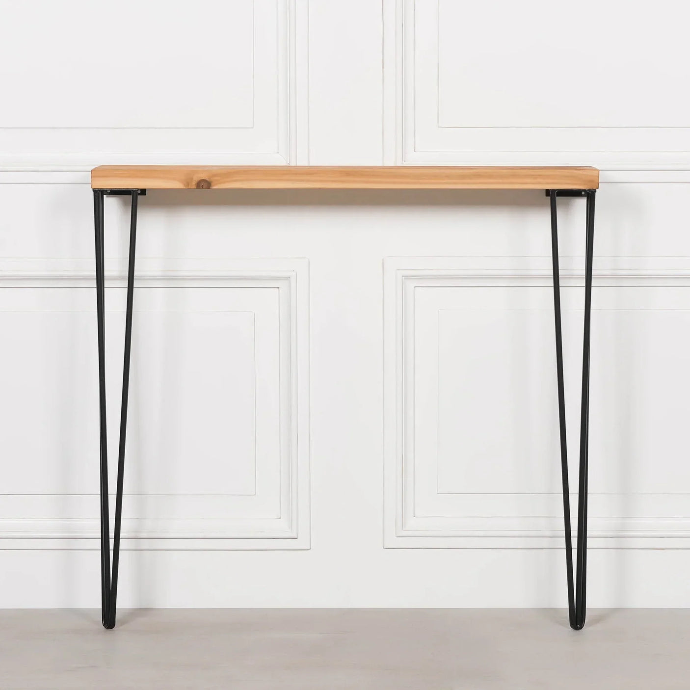 Narrow console table with light wood top and black metal hairpin legs against white wall