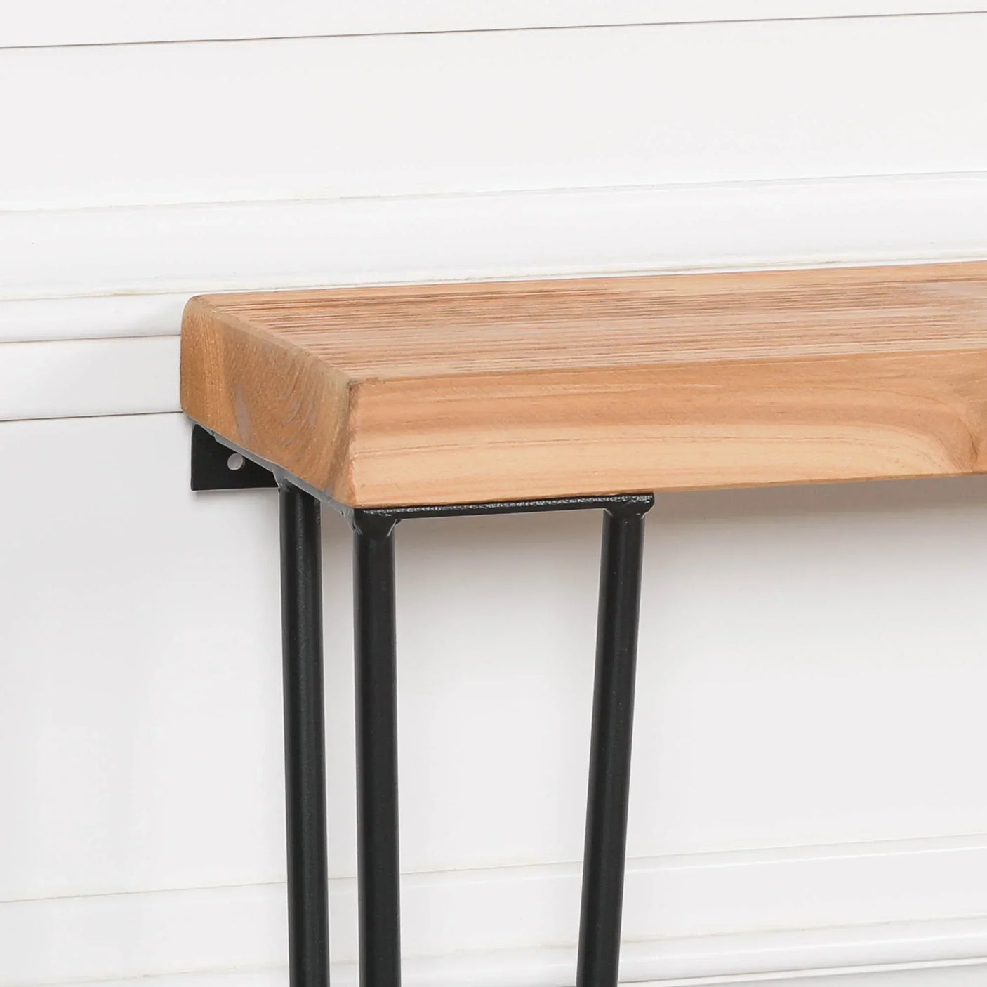Wooden console table top with black metal legs against white panel wall