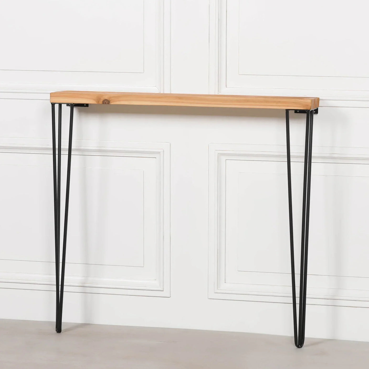 Narrow console table with light wood top and black metal hairpin legs against white wall