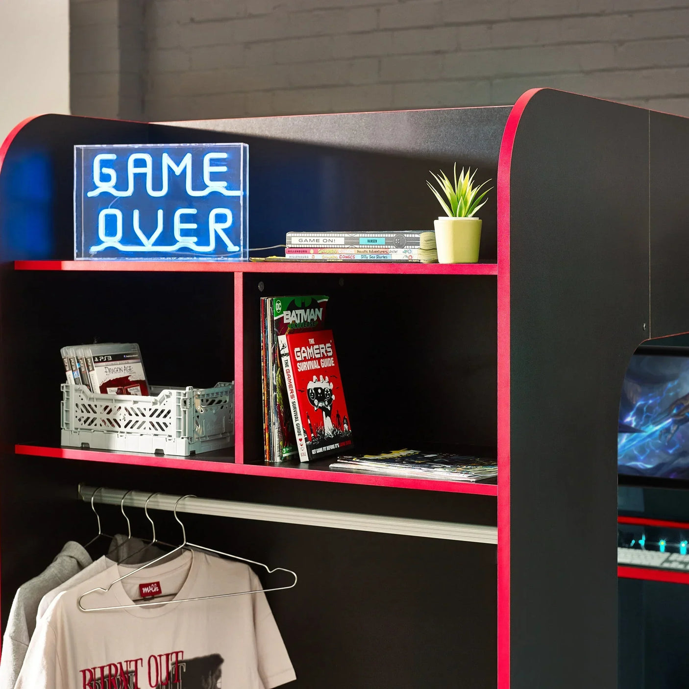 Black shelving unit with red trim, neon game over sign, books, and hanging rail for clothes