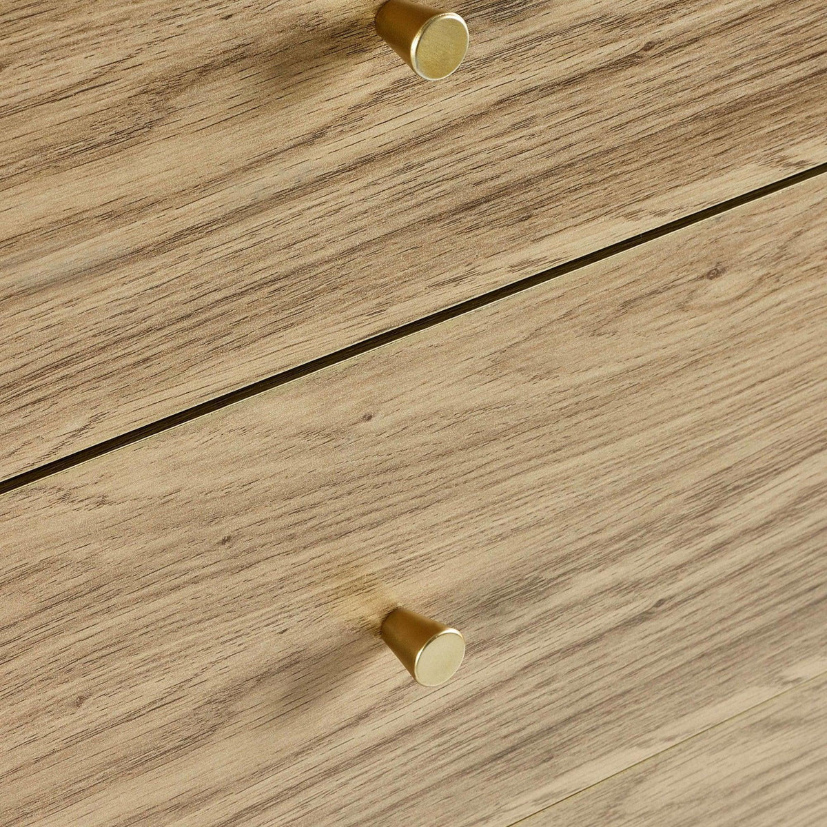Closeup of wood grain drawers with gold handles on a chest of drawers
