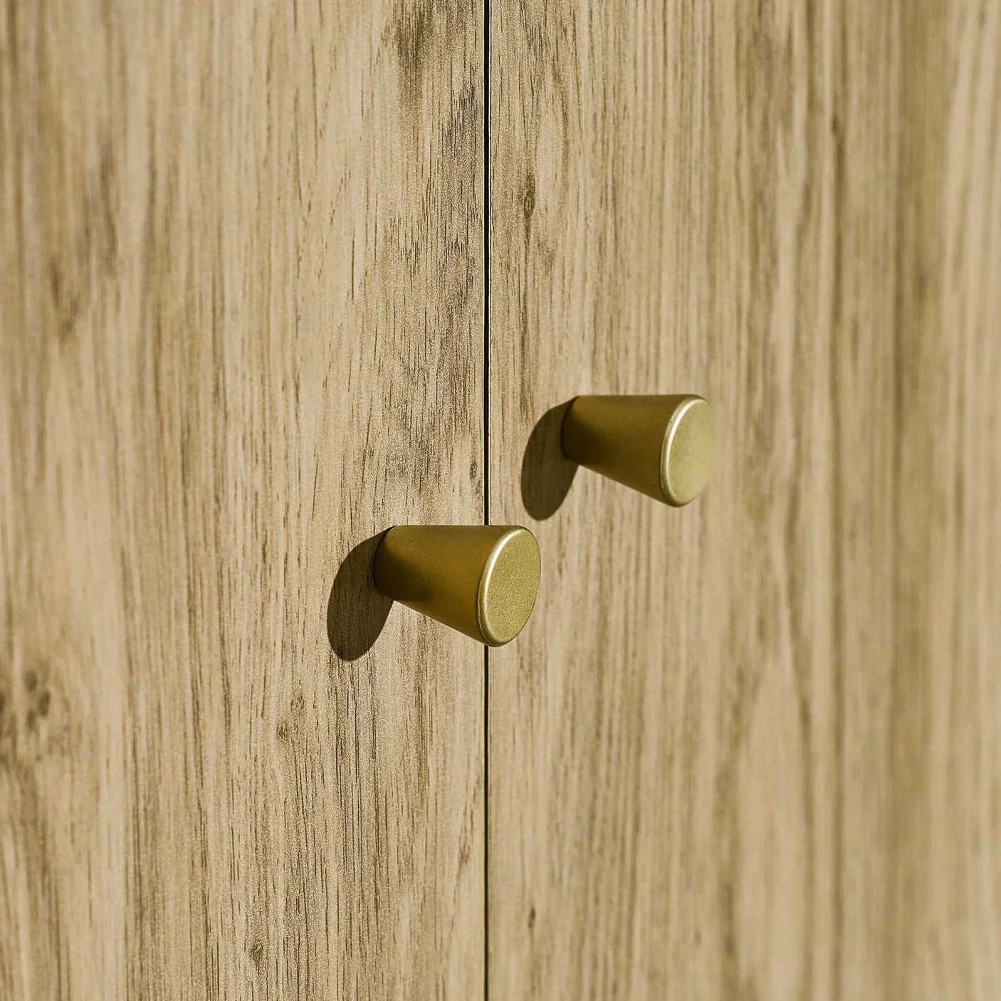 Light oak cabinet doors with gold metal handles in close-up view