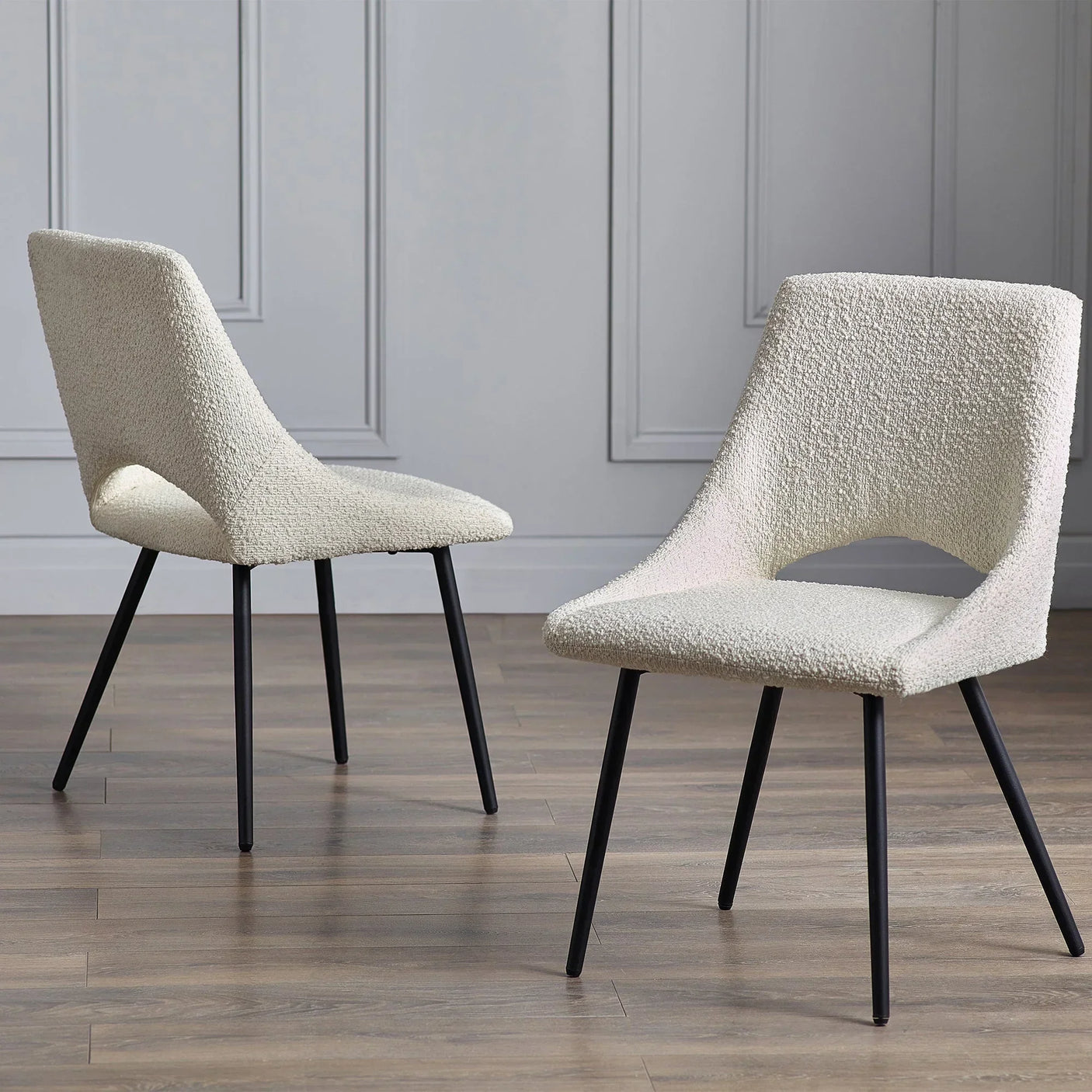 Cream boucle dining chair with black metal legs on wood floor in modern room