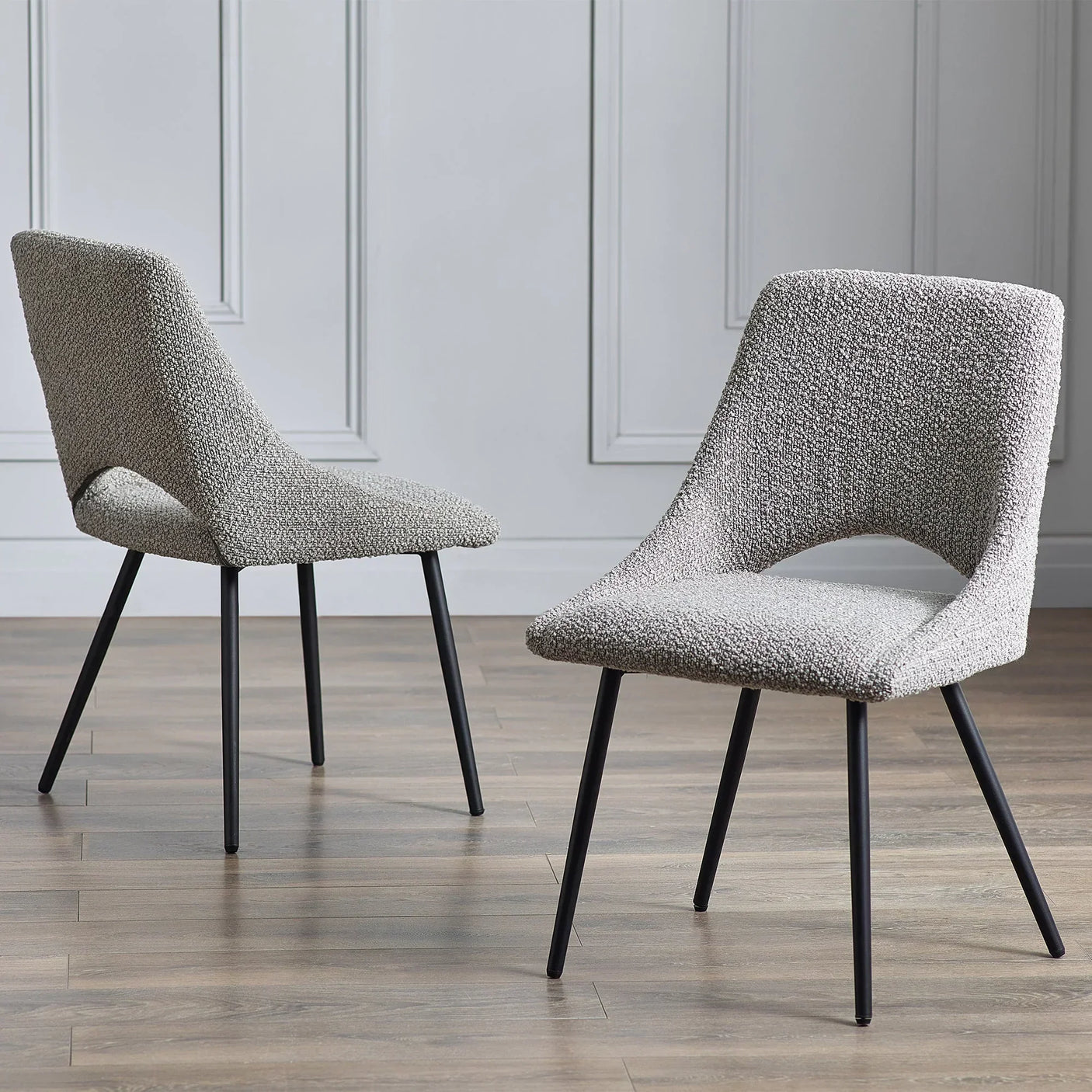 grey boucle dining chairs with black legs on wood floor in modern room