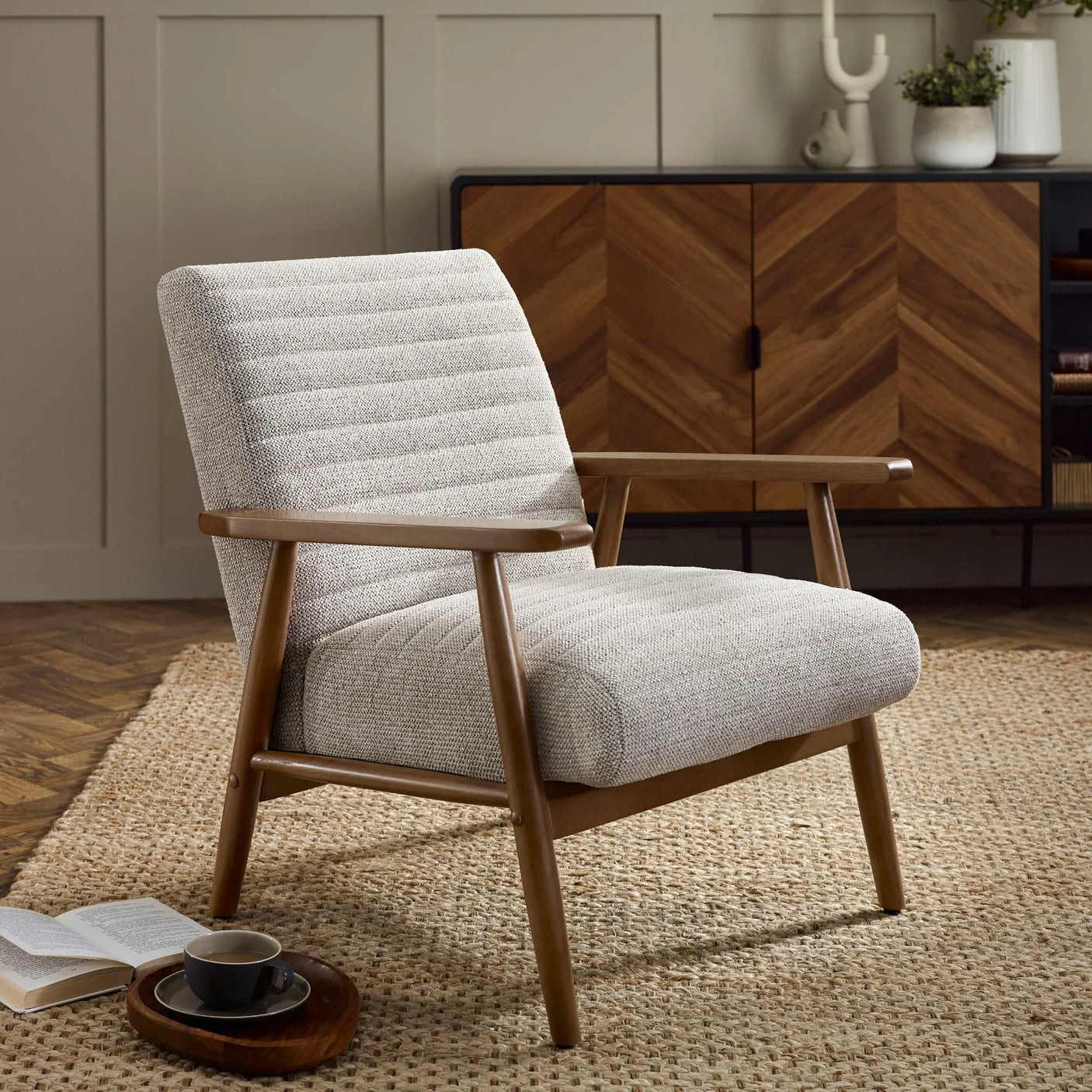 Mid century armchair with grey upholstered seat and wooden frame on woven rug