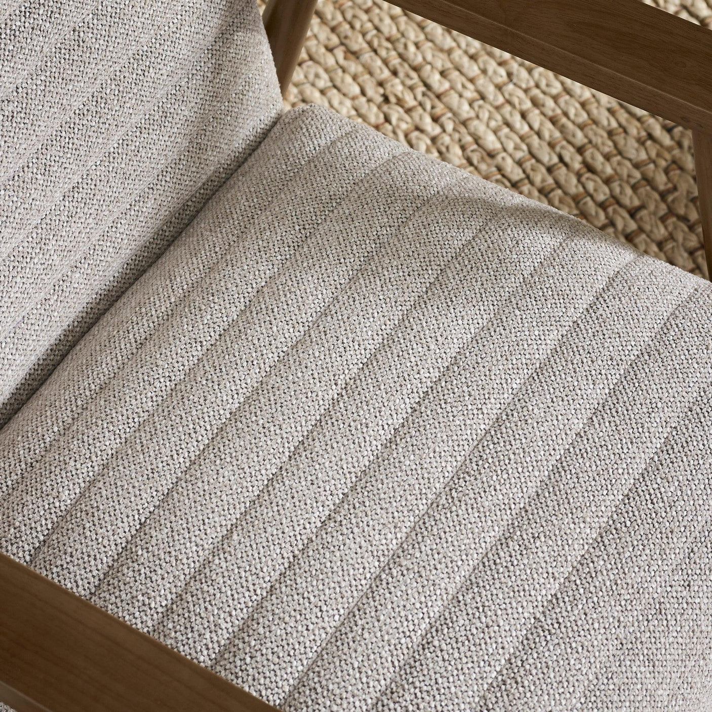 Close view of grey upholstered armchair seat with wood frame and textured fabric detail