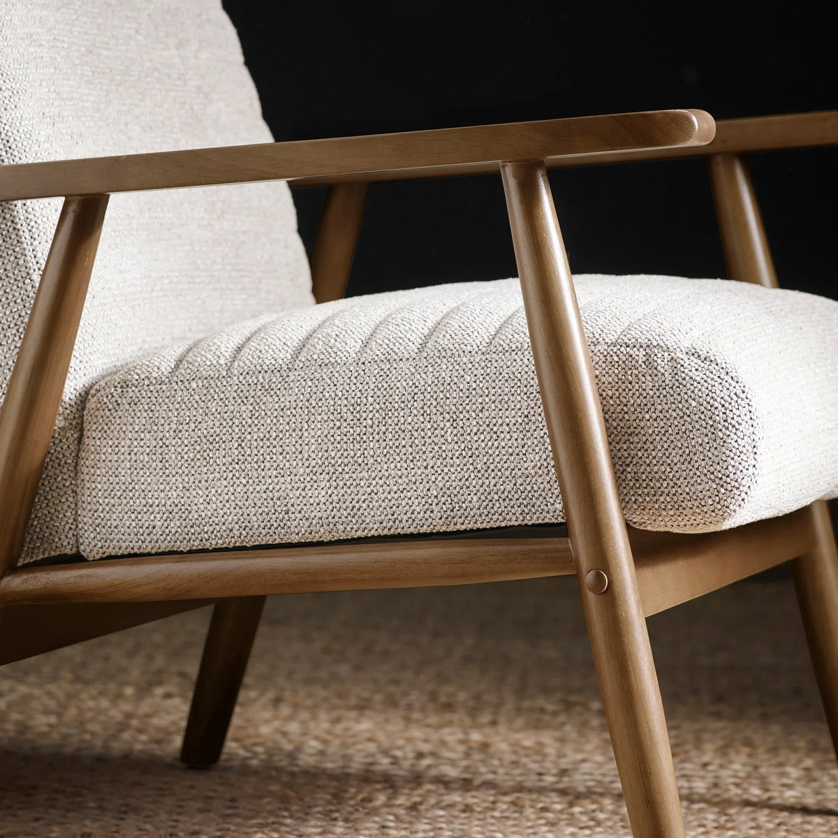 Textured fabric armchair with light wooden frame and neutral cushion, side angle view