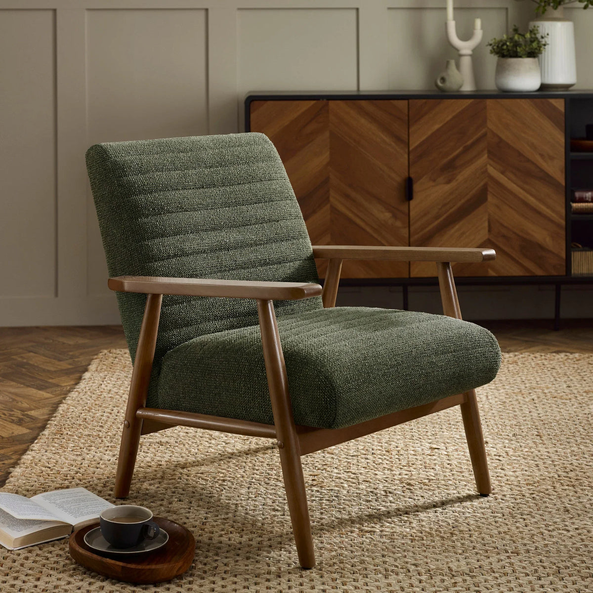 Green fabric accent chair with wooden arms on woven rug in living room setting