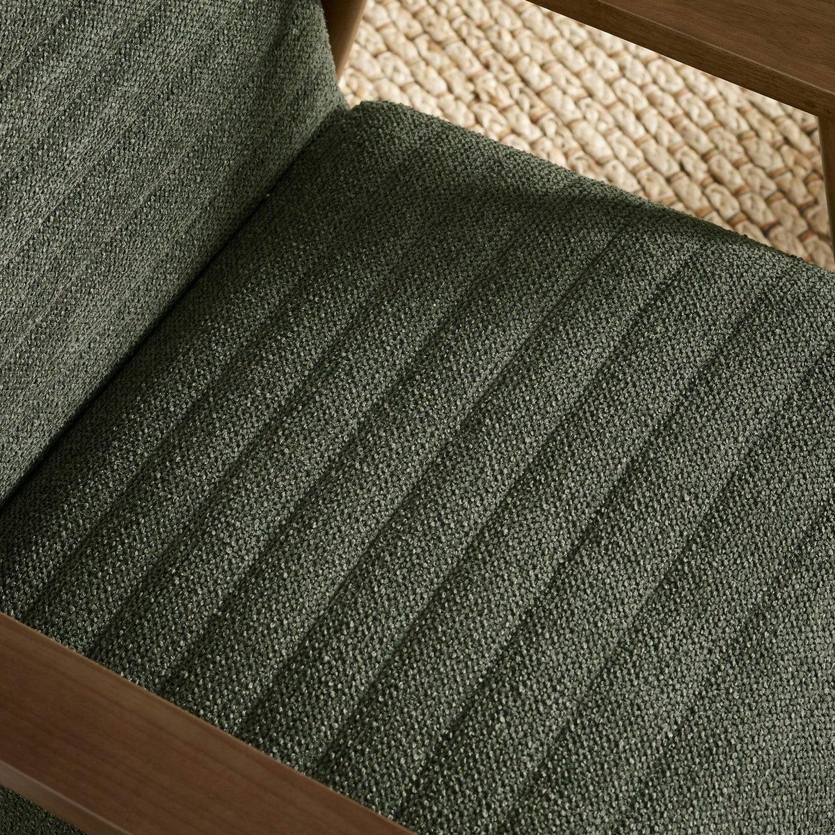 Close-up of green upholstered dining chair seat with textured fabric and wood frame