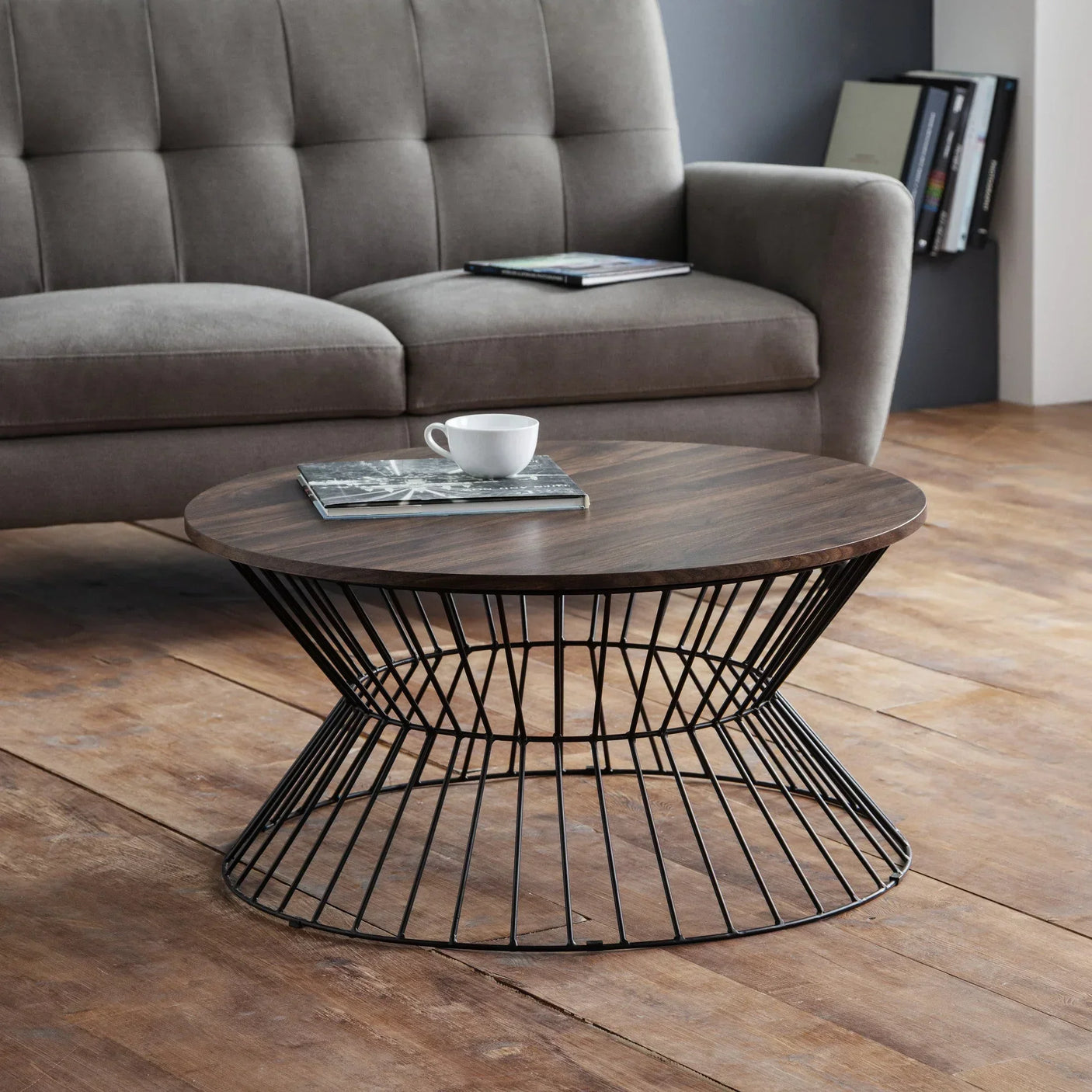 Round coffee table with dark wood top and black wire metal base in modern living room
