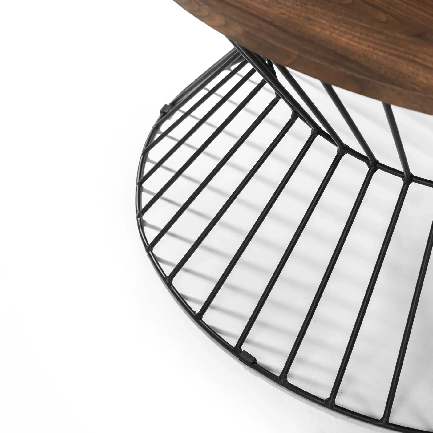 Round coffee table with black metal wire base and dark wood top, side angle view